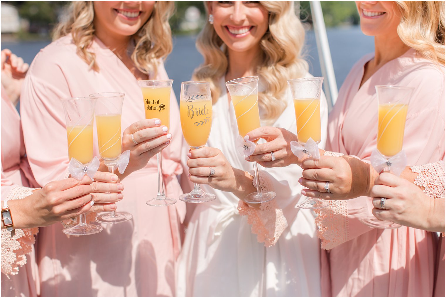 bride and bridesmaids hold custom champagne glasses with mimosas