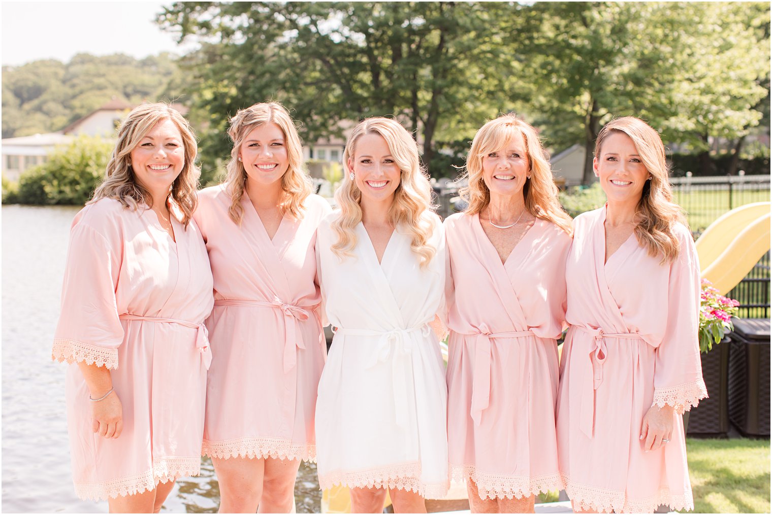 bride hugs bridesmaids in matching pink robes