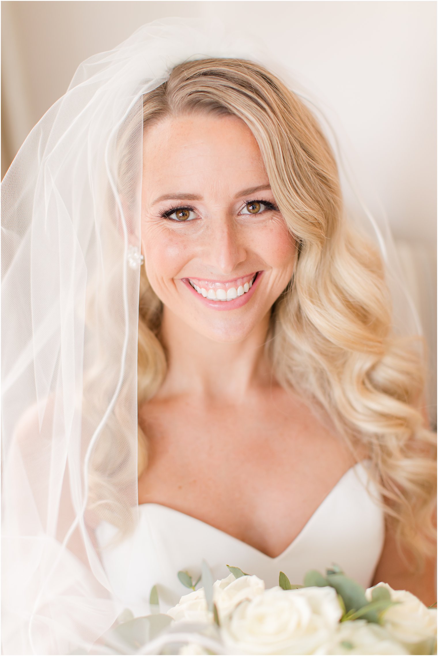 bride smiles wearing veil around shoulders