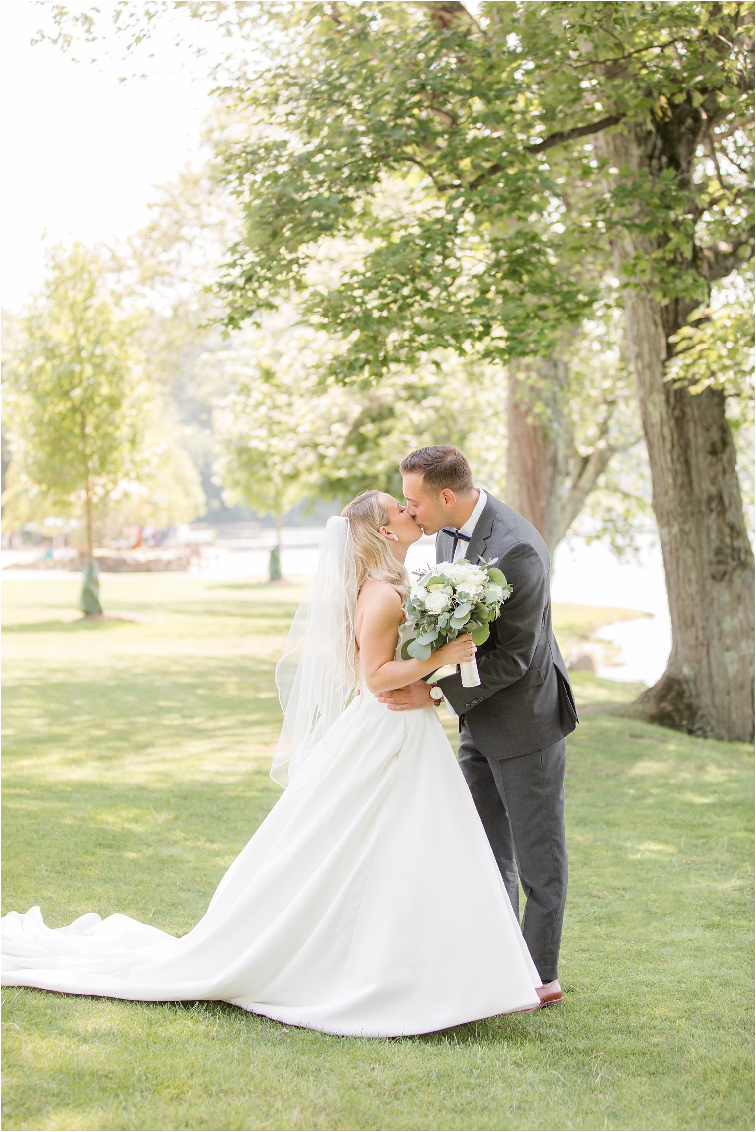 bride and groom kiss by trees at Indian Trail Club