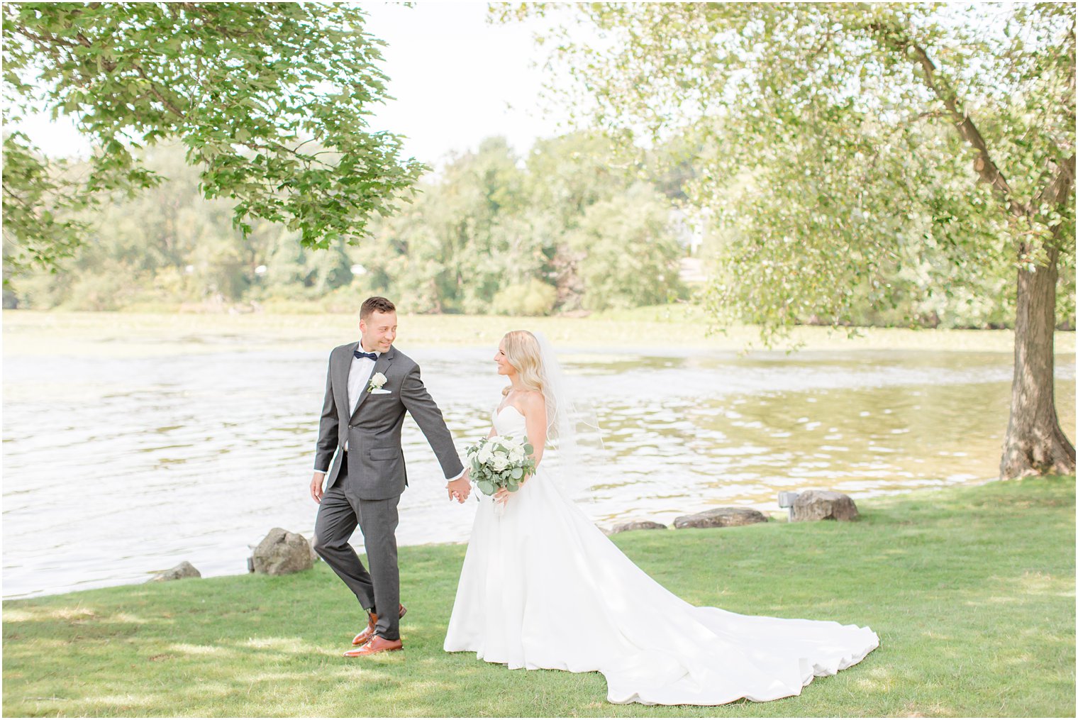 newlyweds walk by water at Indian Trail Club on wedding day