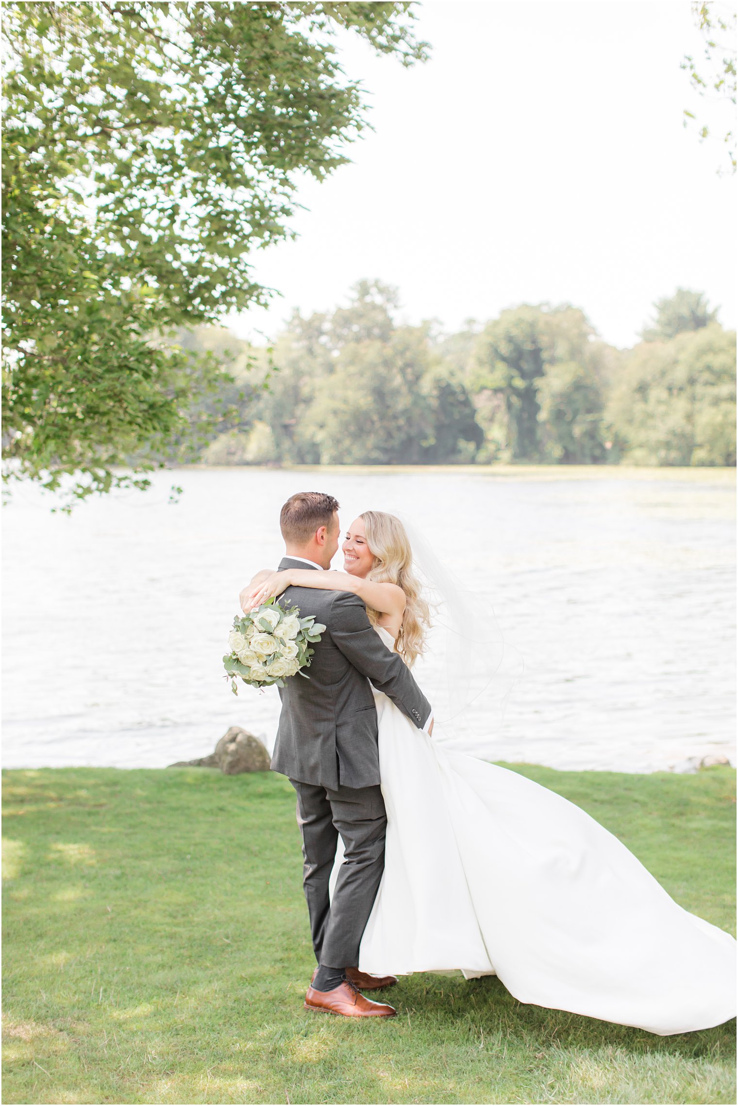 bride hugs groom around shoulders with bouquet