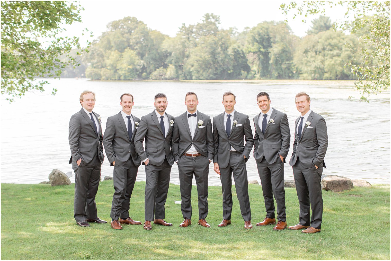 groom poses with groomsmen in grey suits with navy ties