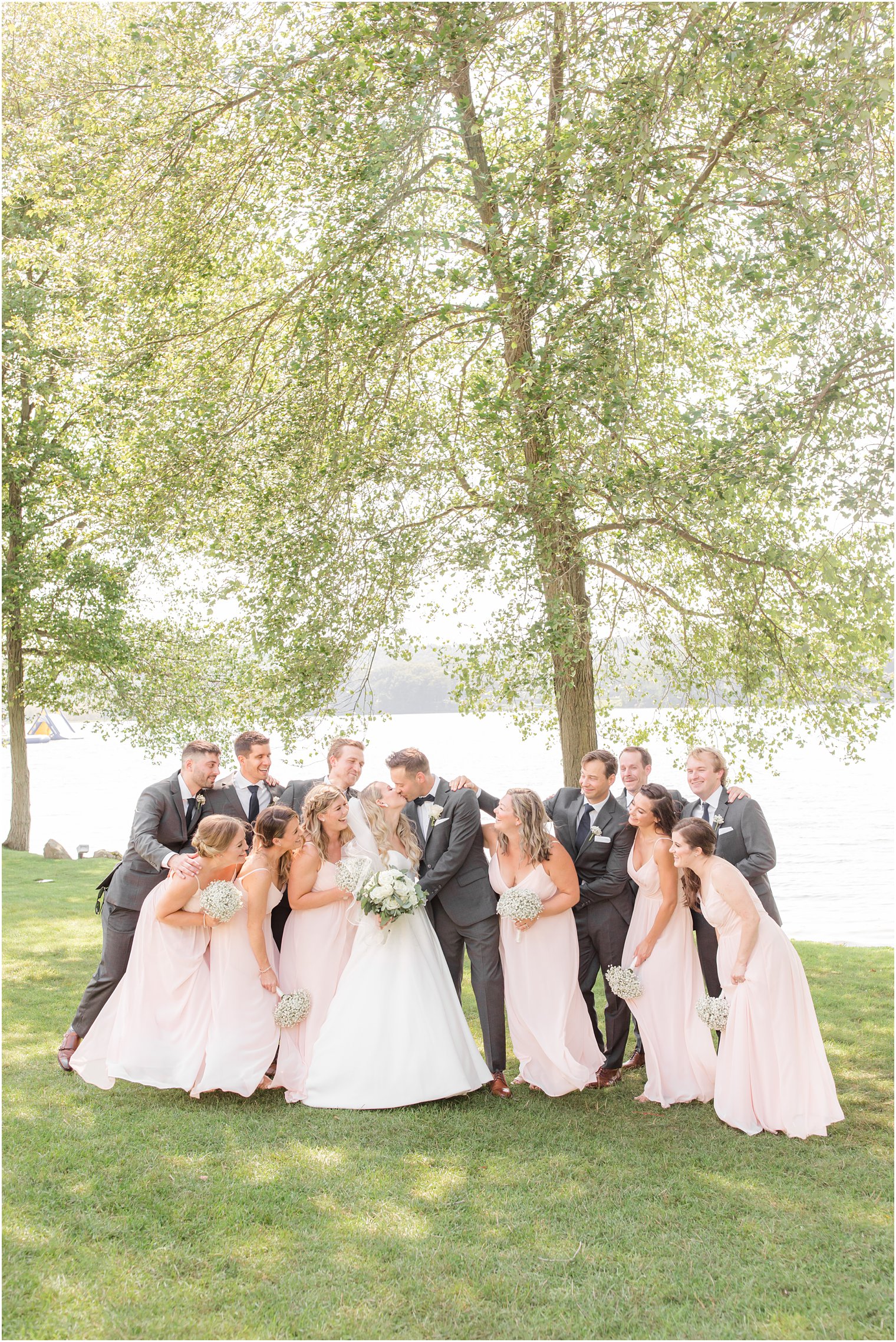 newlyweds kiss with wedding party around them at Indian Trail Club