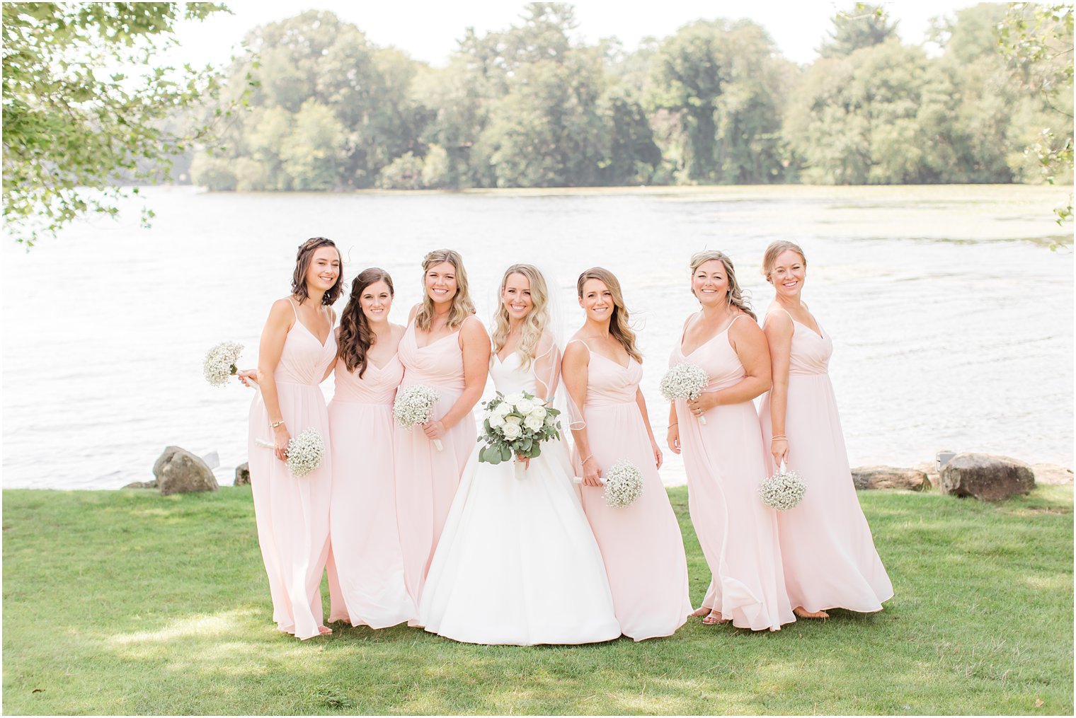 bride poses with bridesmaids in light pink gowns