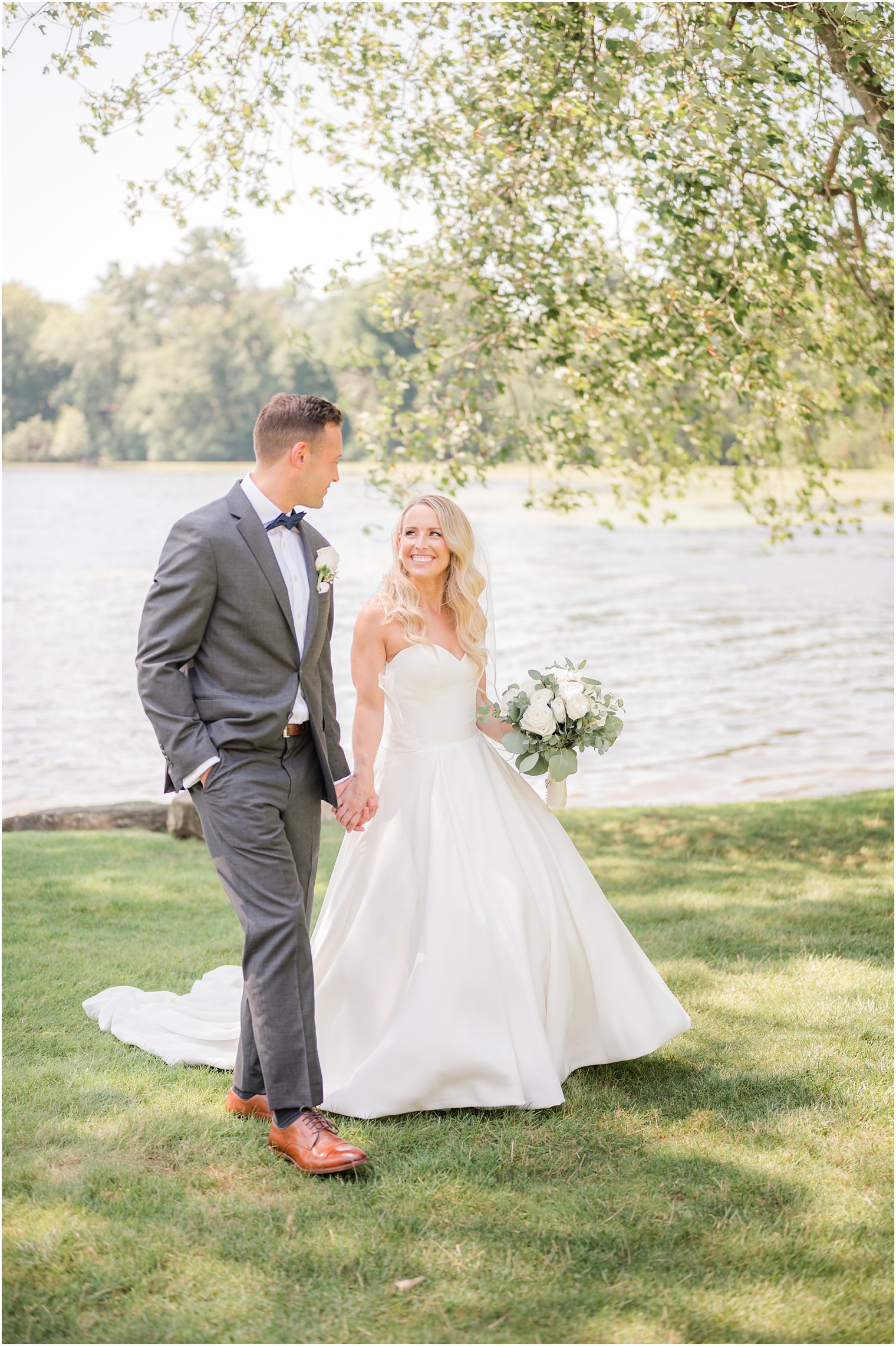 bride and groom hold hands walking along waterfront at Indian Trail Club