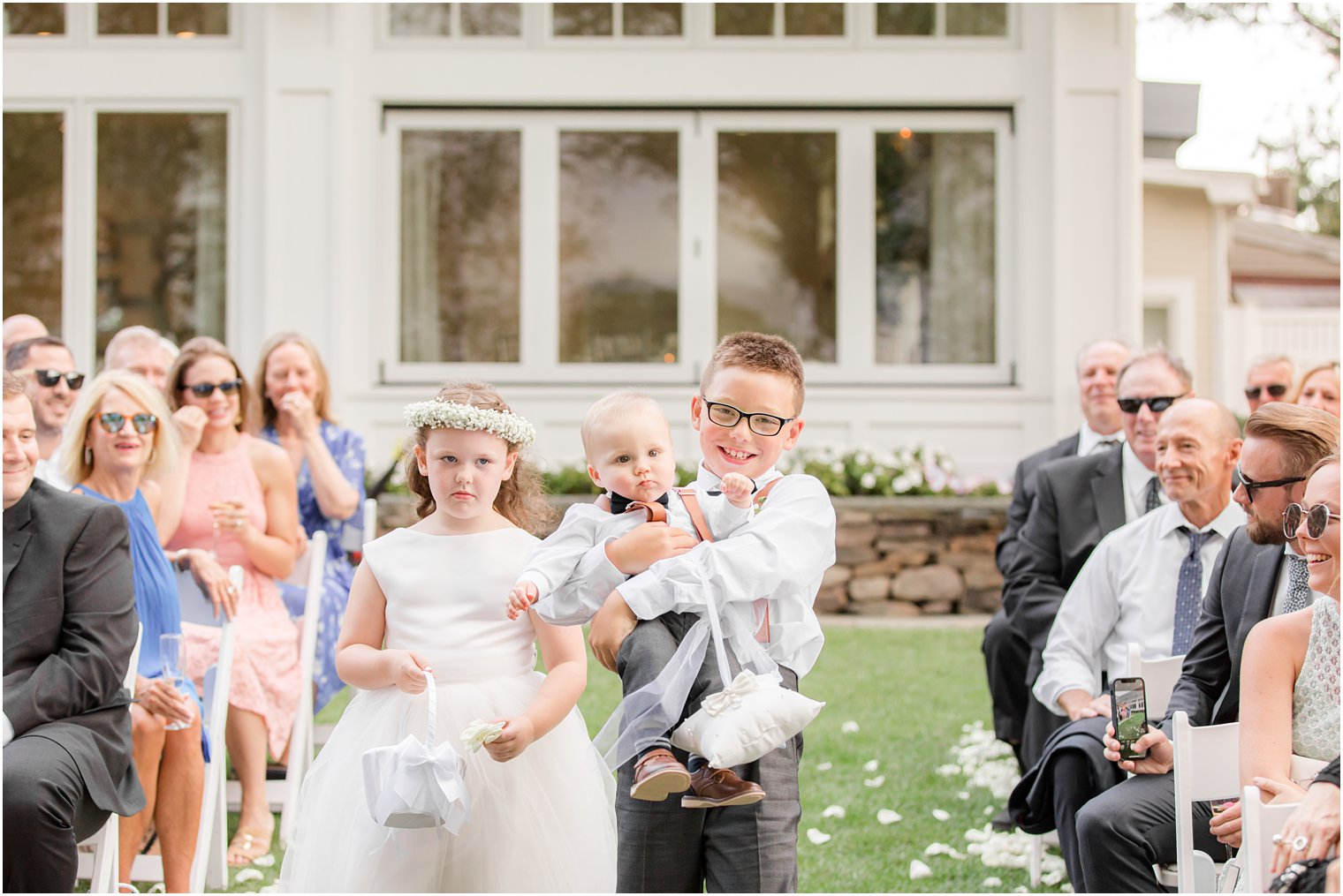 ring bearer carries baby down aisle with flower girl