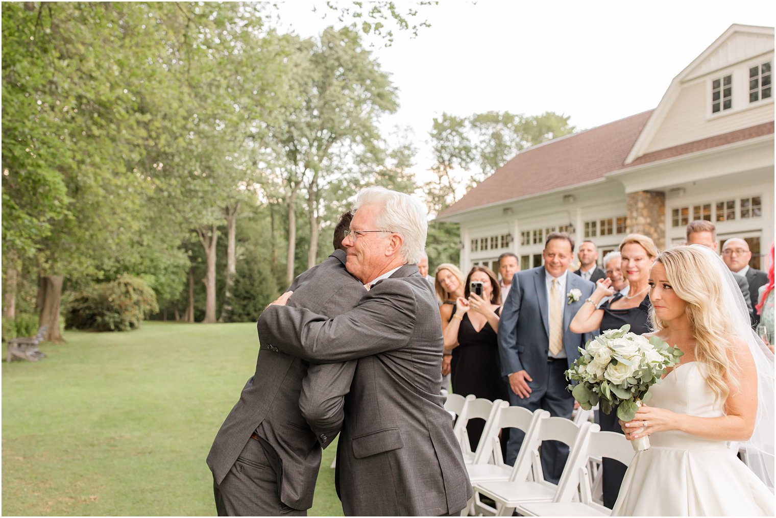 dad hugs groom during outdoor wedding ceremony in Franklin Lakes