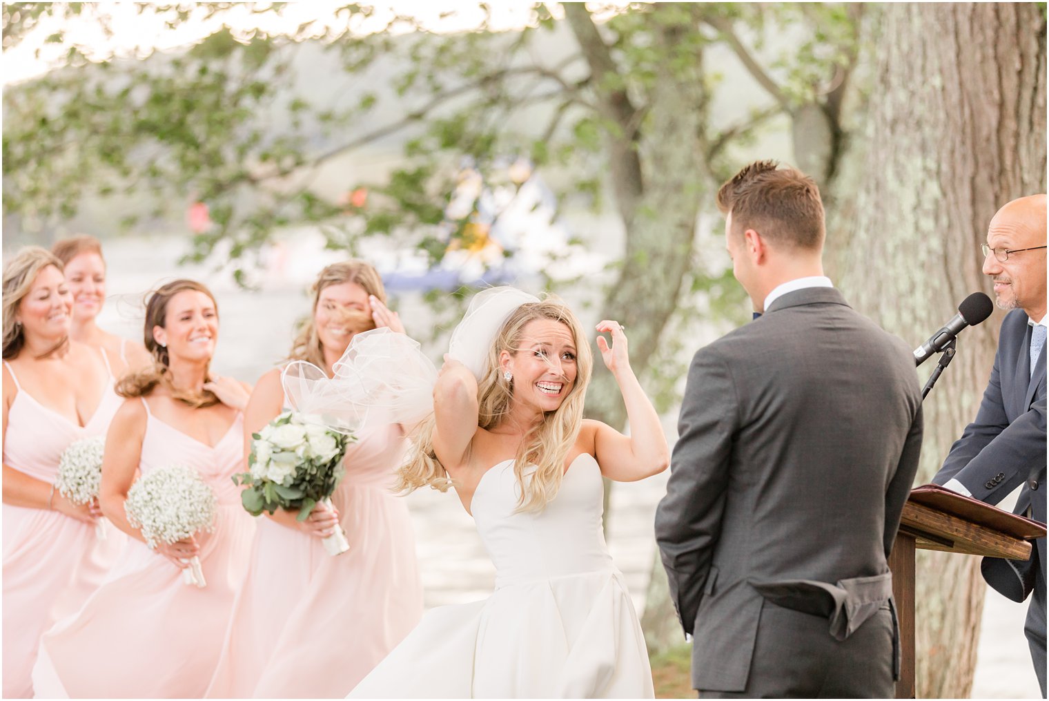 bride holds onto veil during windy outdoor wedding ceremony in Franklin Lakes