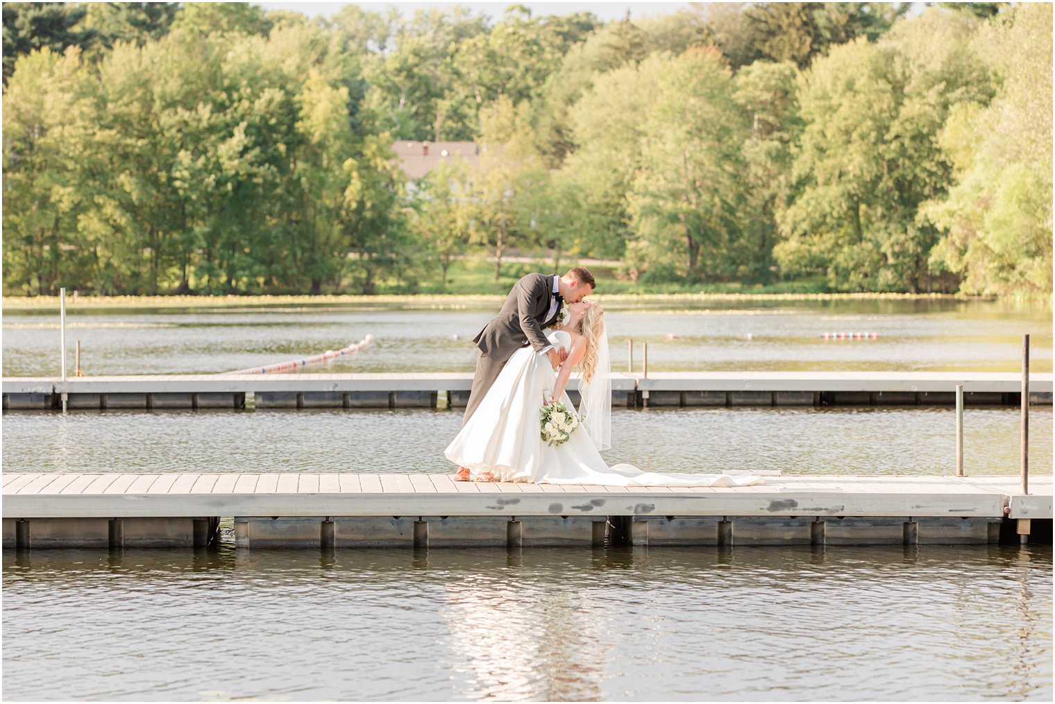groom dips bride during wedding photos on dock at Indian Trail Club