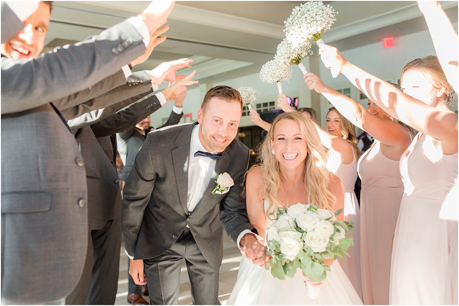 bride and groom walk through tunnel of wedding party