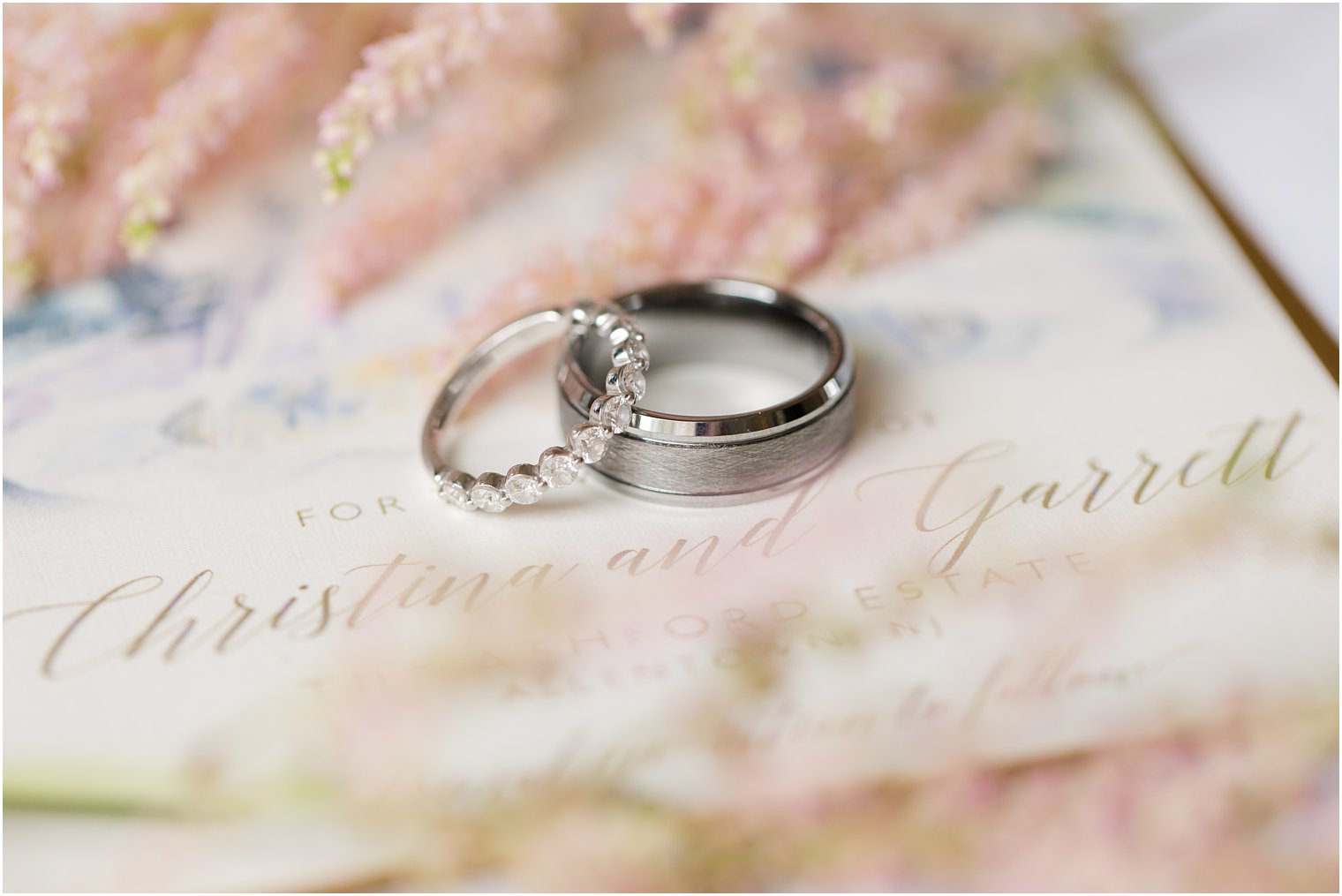 wedding rings rest on watercolor wedding invitations 