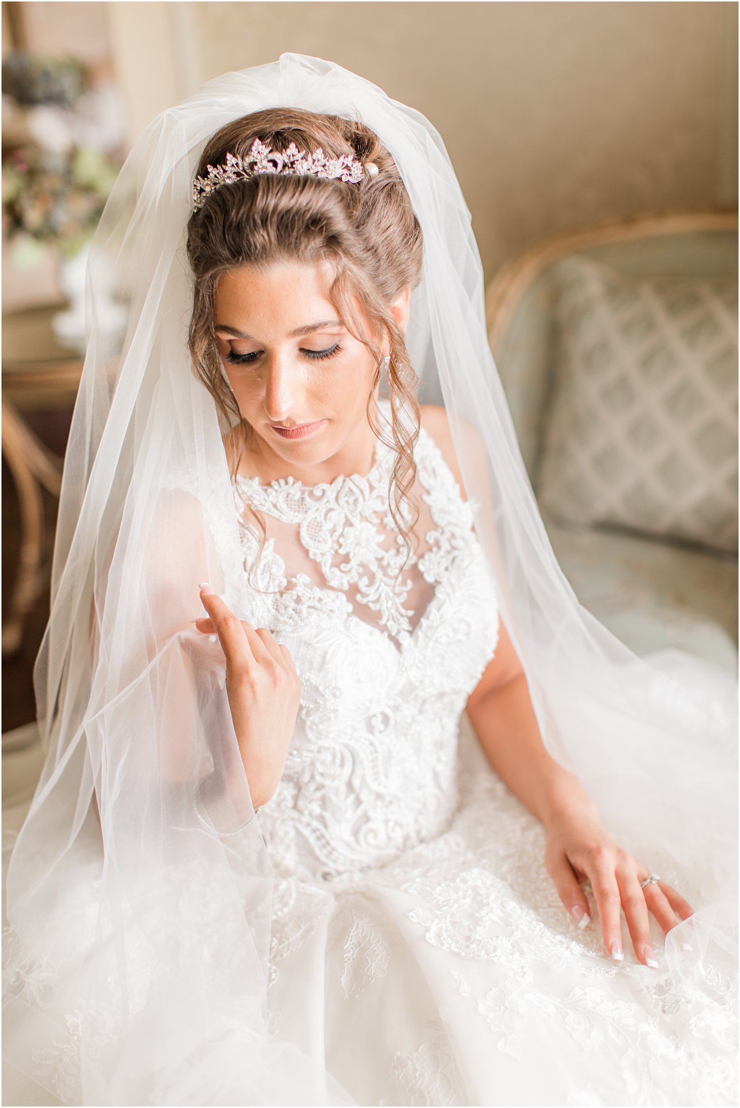 bride sits in wedding gown with veil around shoulders