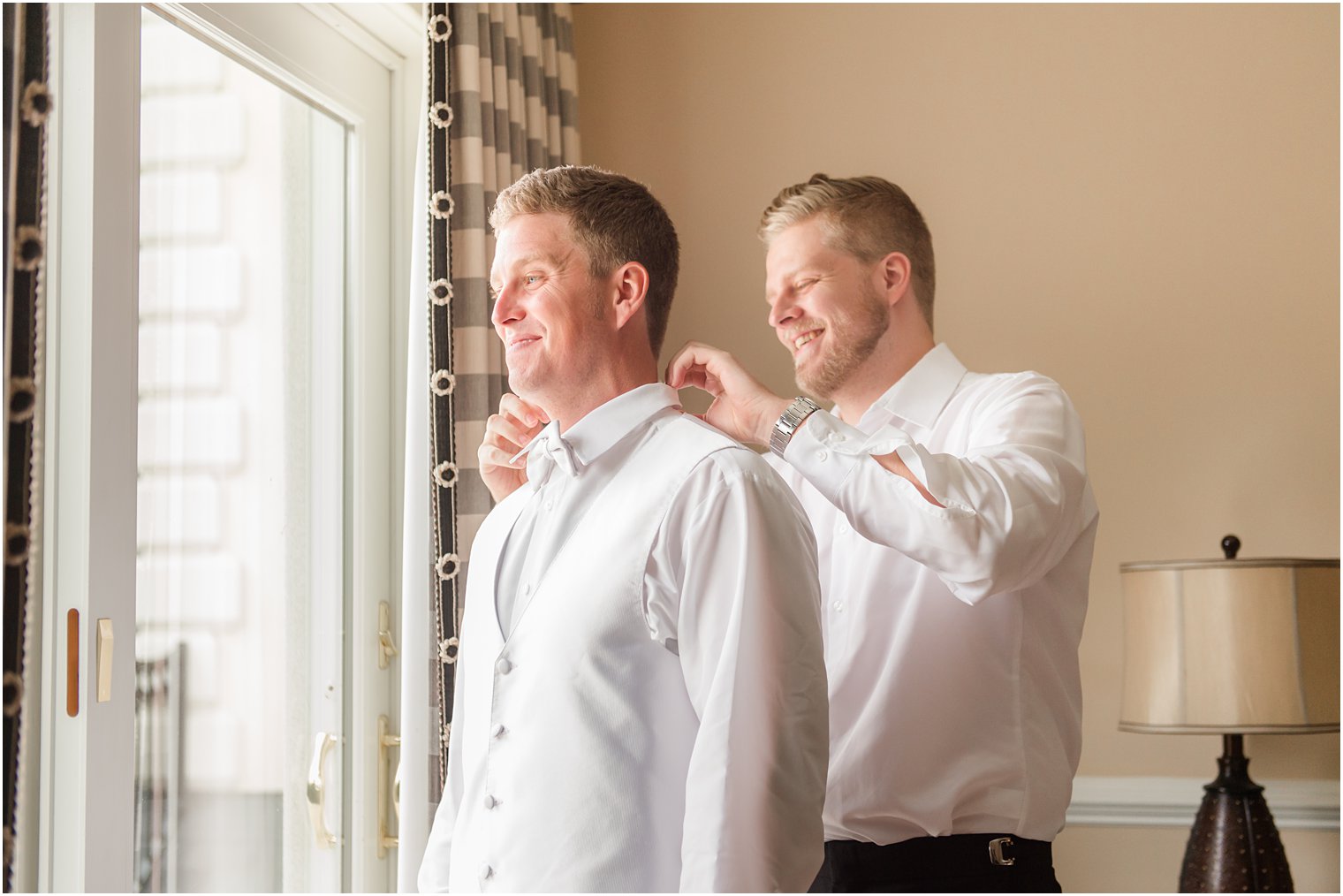 groomsman adjusts tie for groom on NJ wedding day