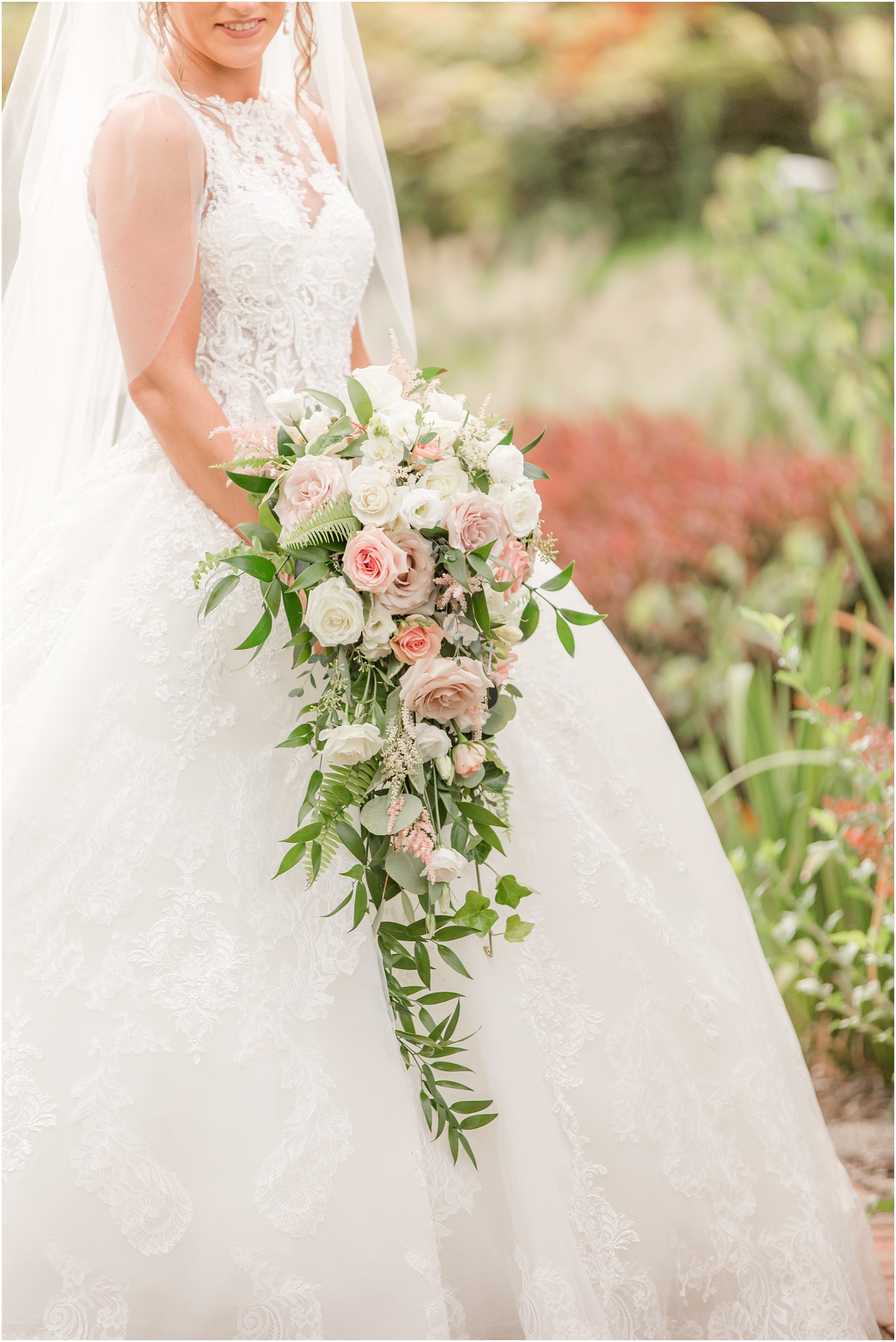 bride holds cascading bouquet of white and pink roses 