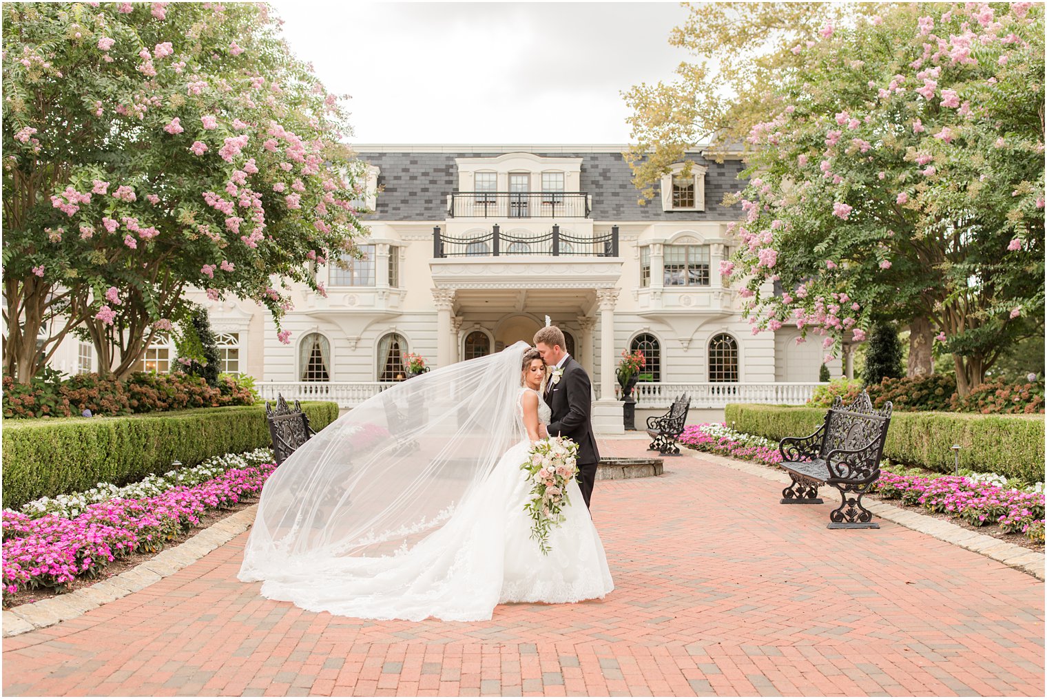groom kisses bride's forehead with her veil floating behind them at Ashford Estate