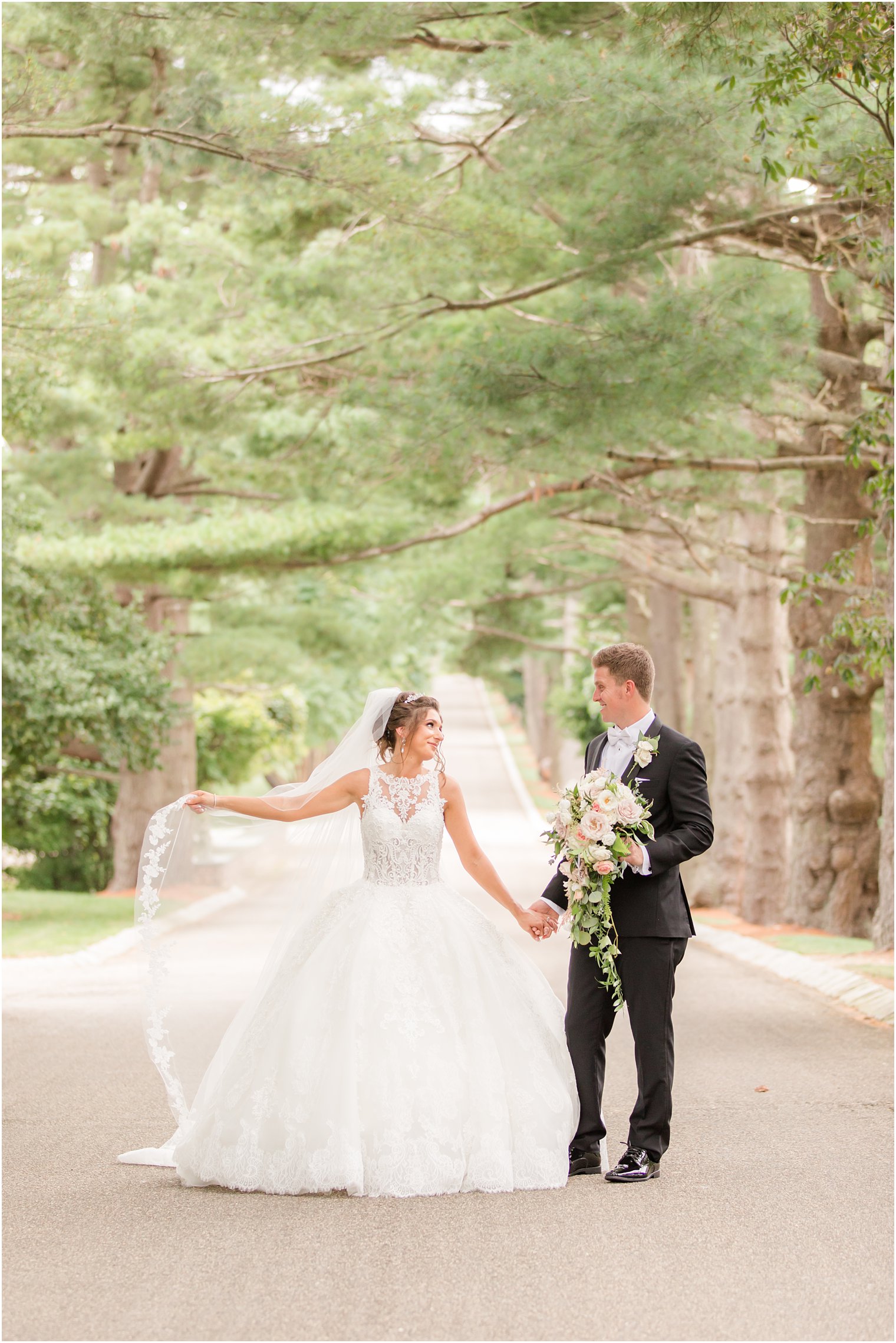 bride holds veil out during portraits on driveway at Ashford Estate