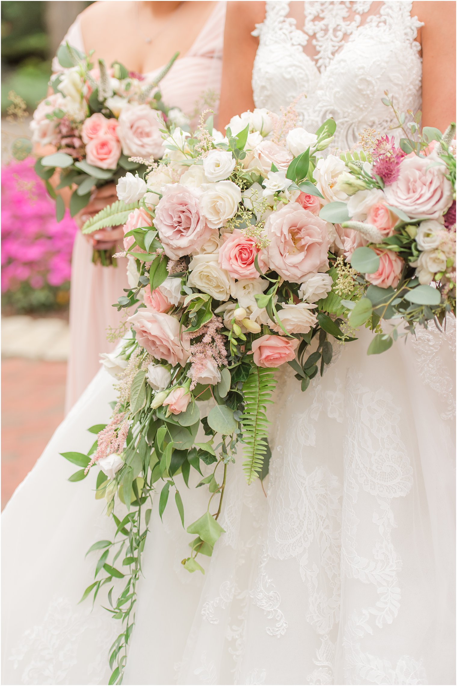 bride holds cascading bouquet of pink roses