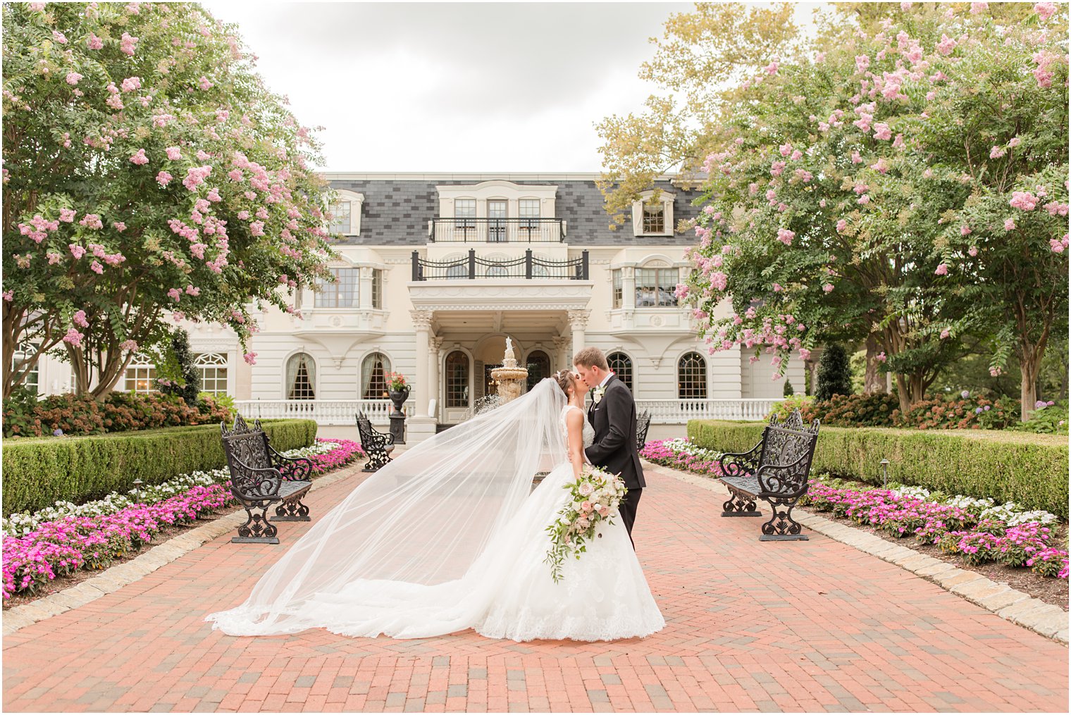 bride and groom kiss outside Ashford Estate with bride's veil floating