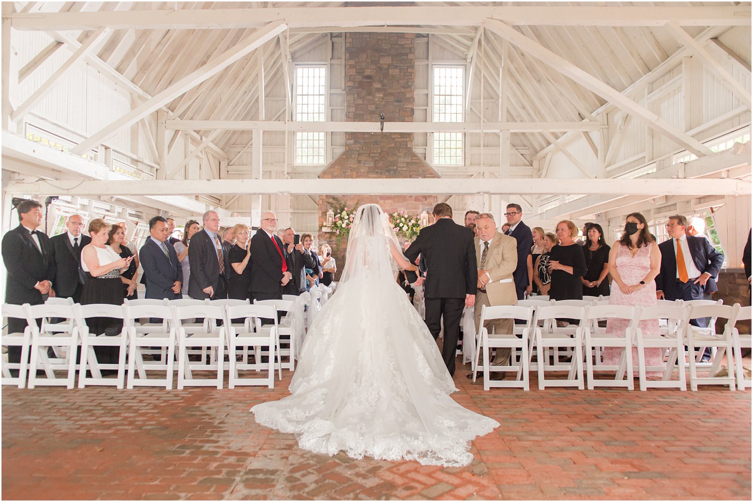 bride in ballgown with veil walks down aisle at Ashford Estate