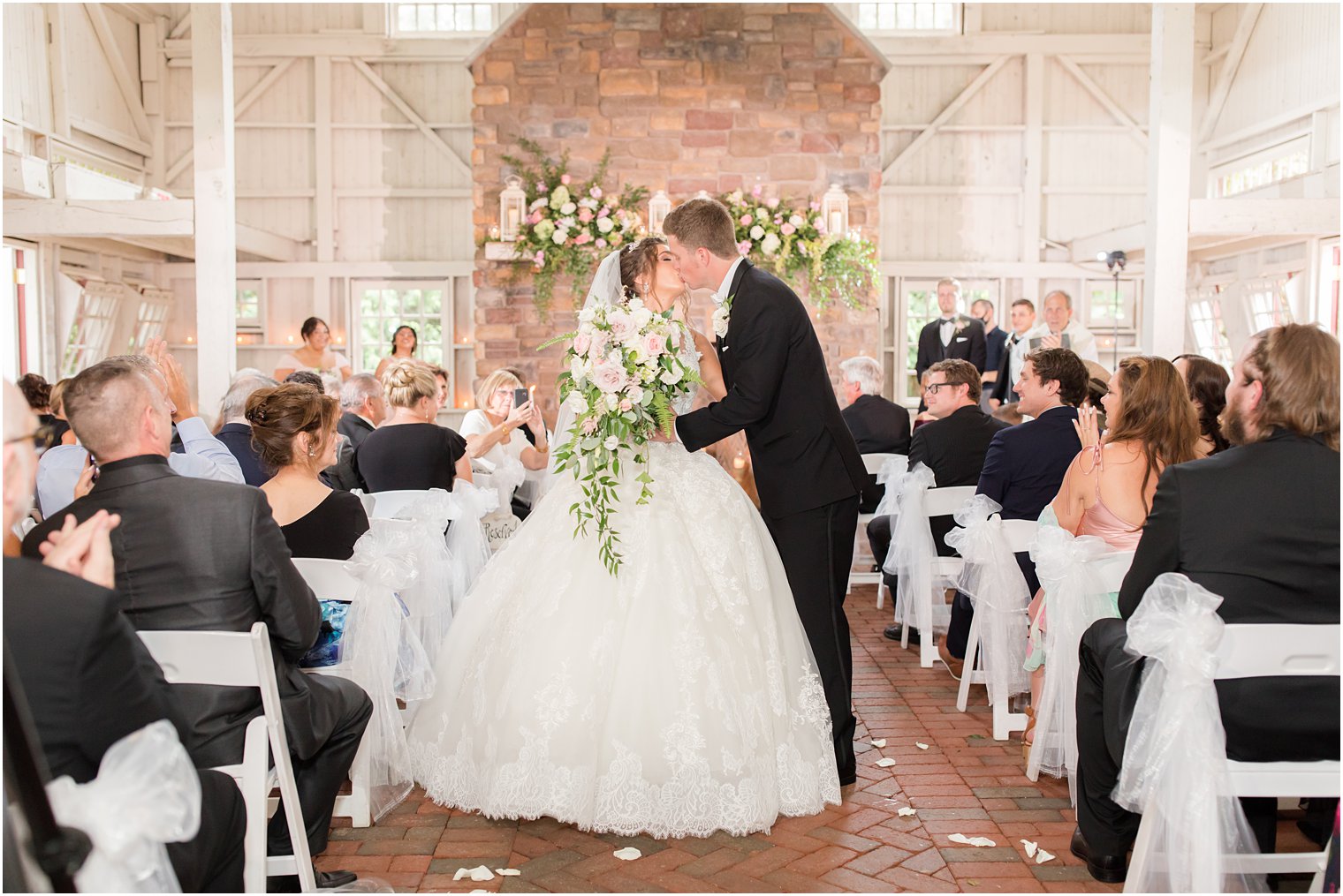 bride and groom kiss walking up aisle after ceremony in barn at Ashford Estate