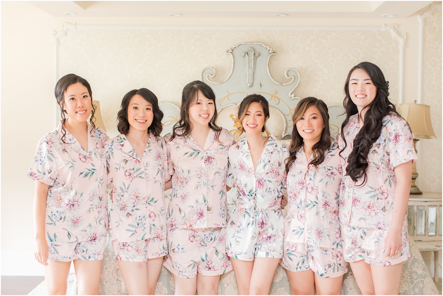 bride hugs bridesmaids in matching pink floral pajamas before NJ wedding