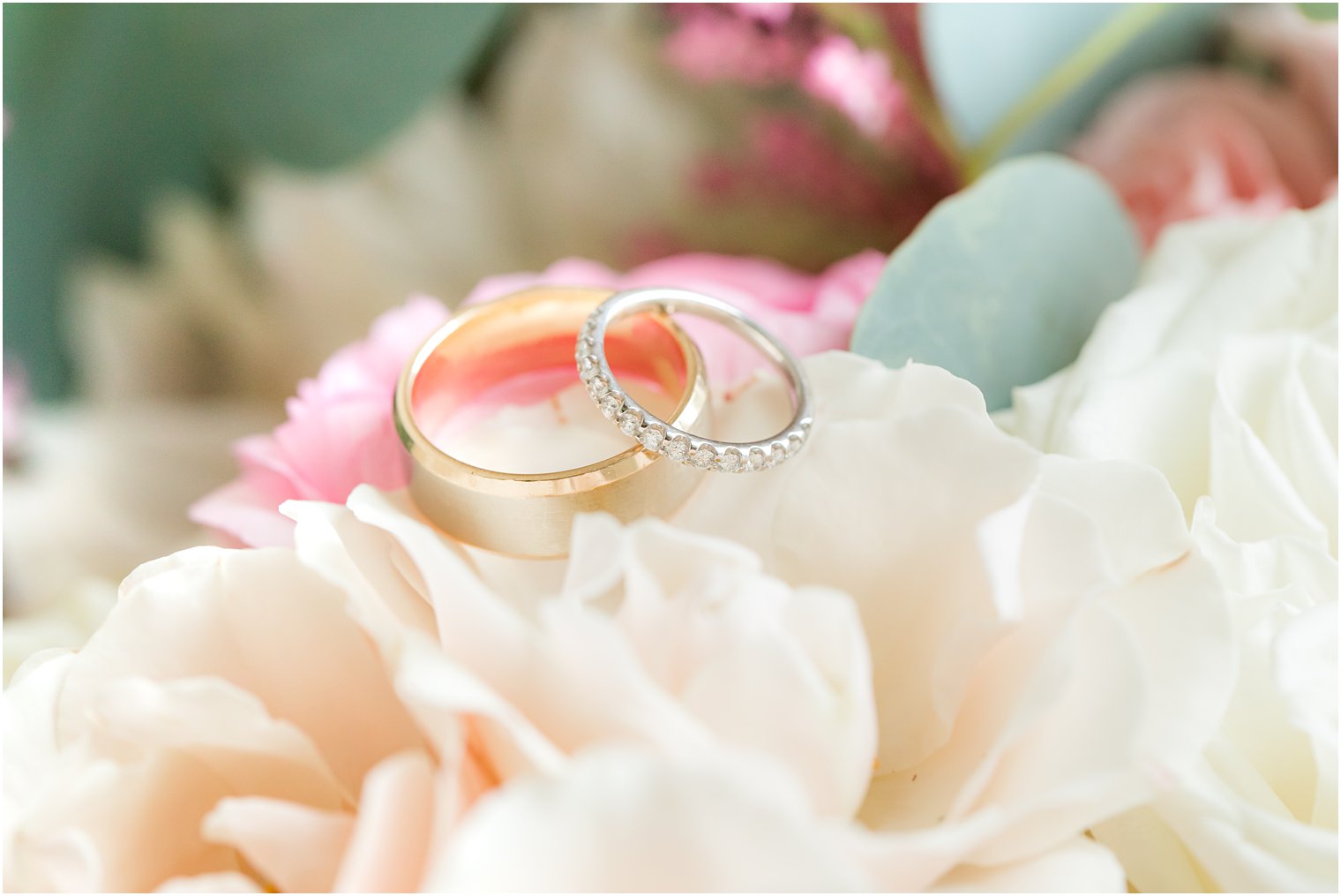 wedding bands rest on white flowers before NJ wedding