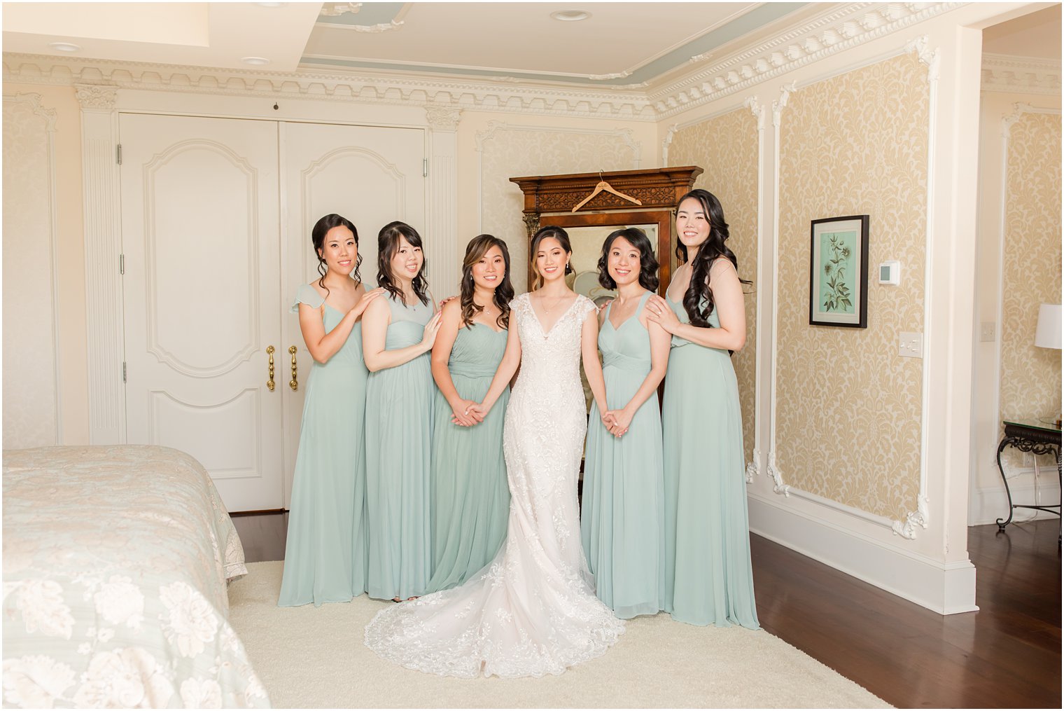 bride stands with five bridesmaids in sage green dresses