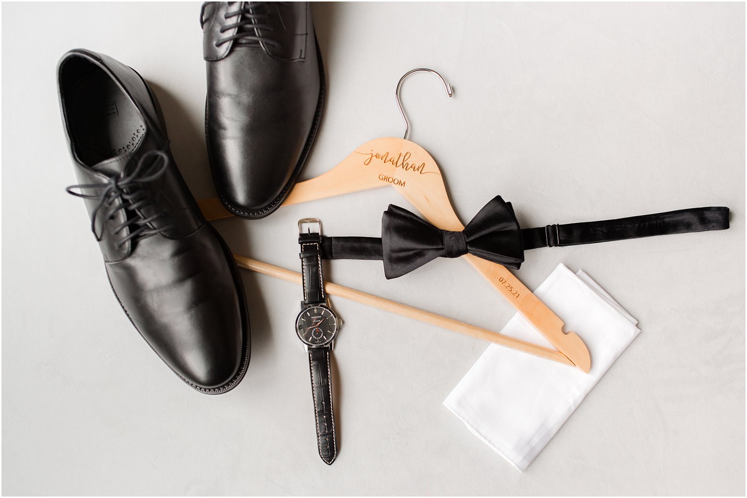 groom's shoes and black tie on wooden hanger