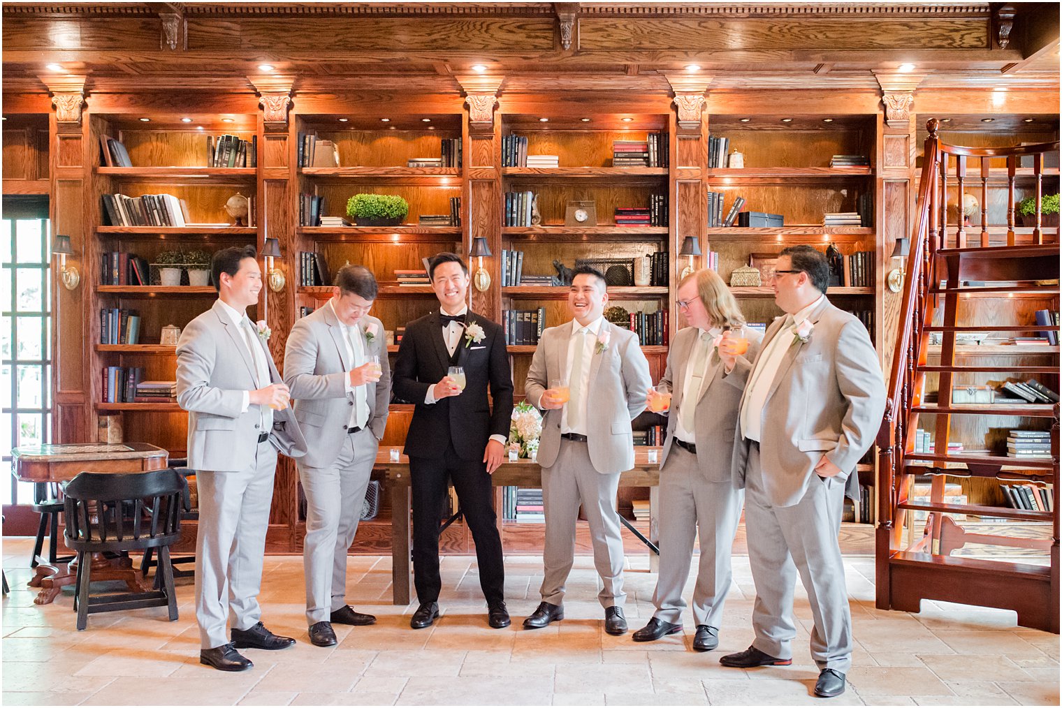 groom laughs with groomsmen in library of Ashford Estate