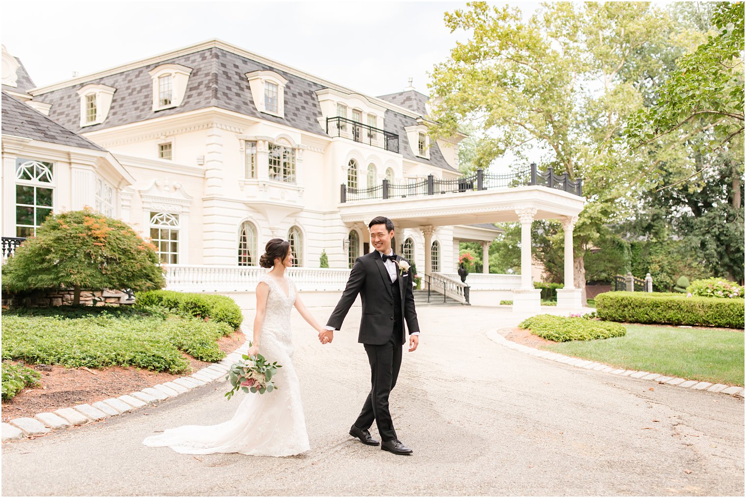 newlyweds hold hands walking outside Ashford Estate