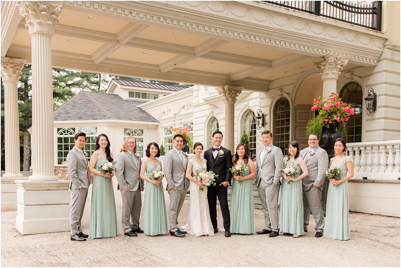 bride and groom pose with wedding party in grey and sage green outside Ashford Estate
