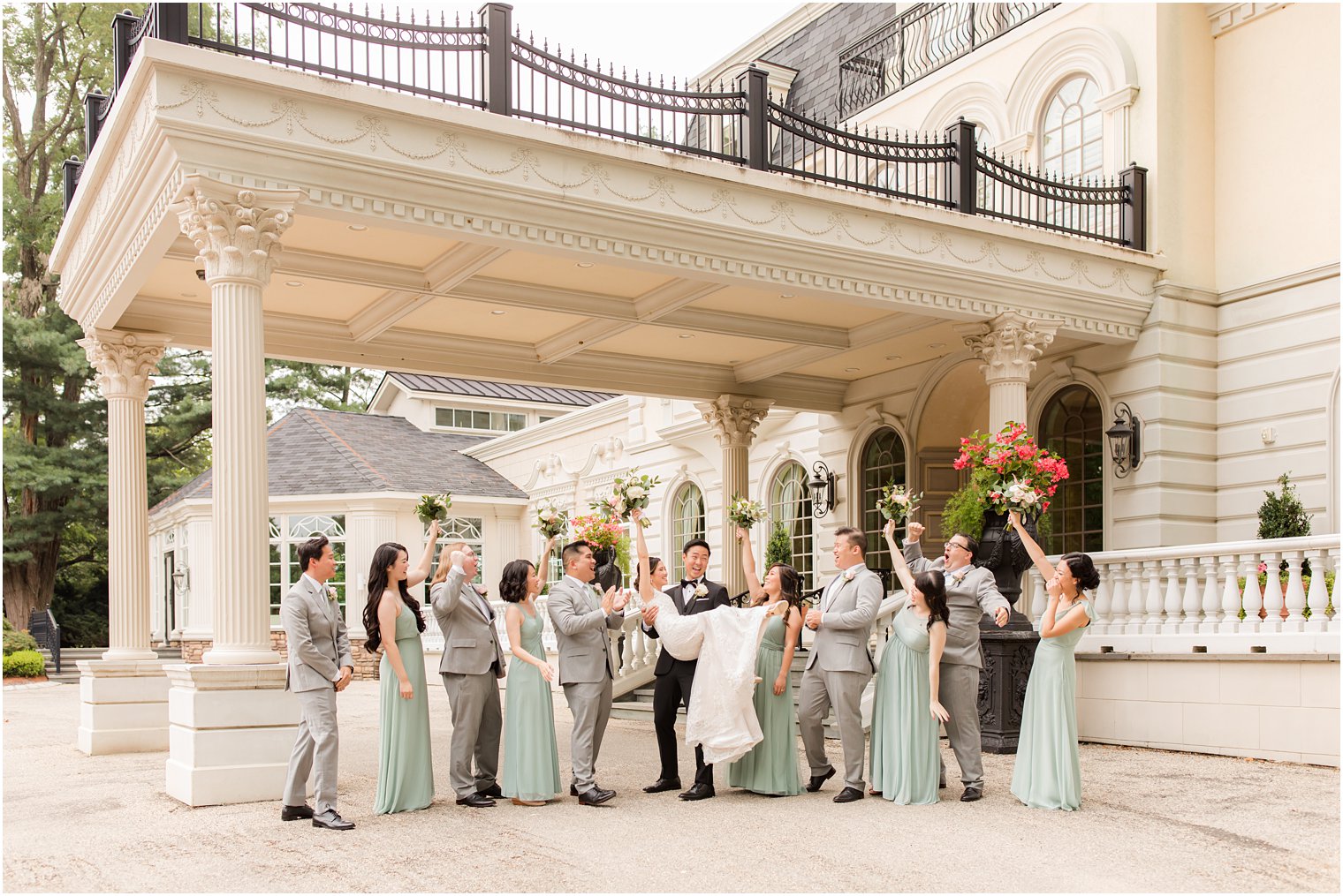 wedding party cheers while groom lifts bride up during portraits outside Ashford Estate