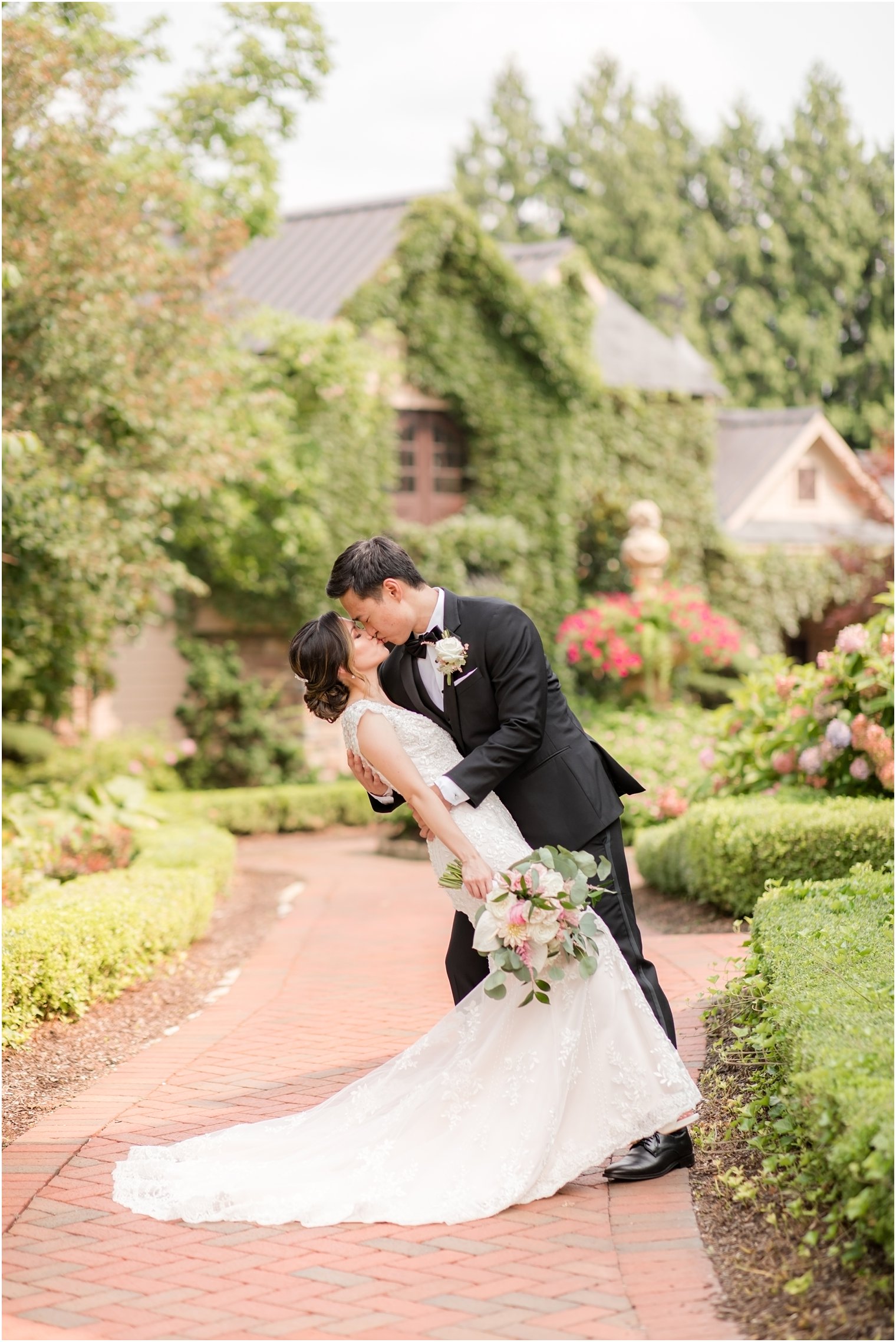 groom kisses bride dipping her in gardens of Ashford Estate