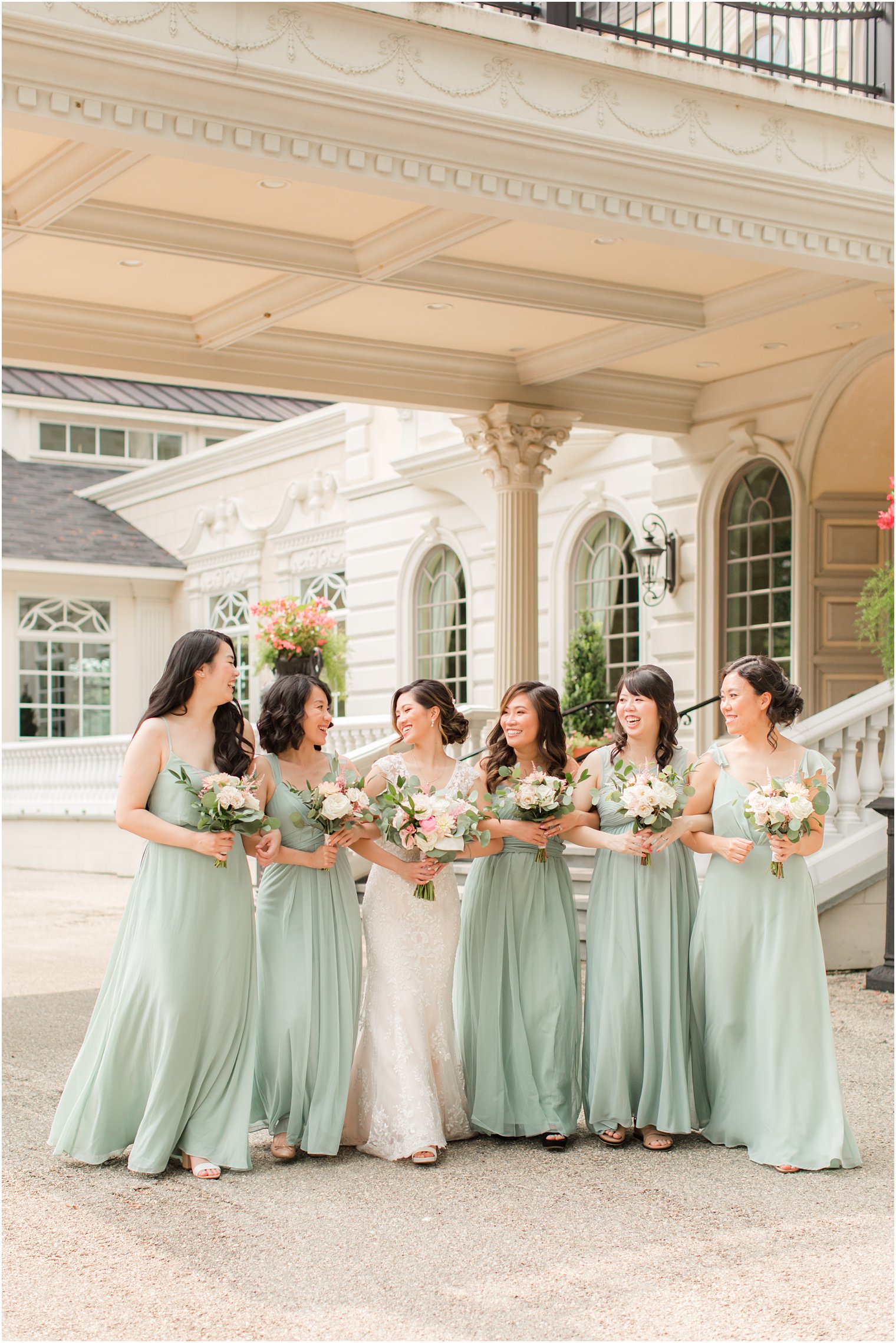 bride walks with bridesmaids in sage green dresses outside Ashford Estate