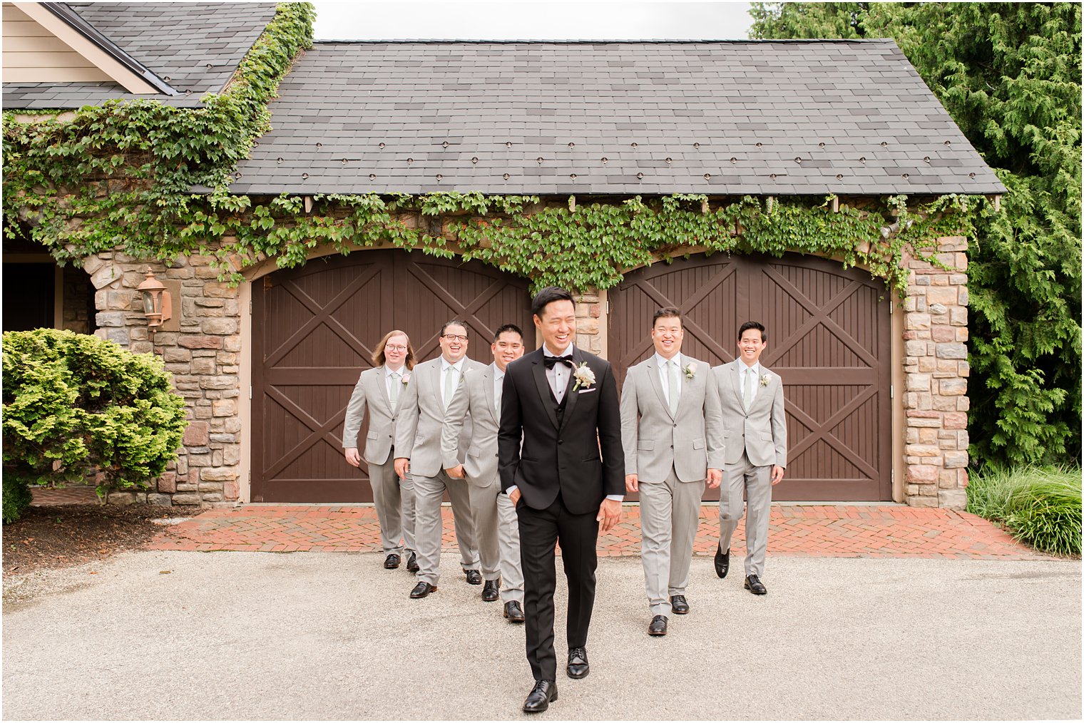groom walks with five groomsmen in grey suits behind him