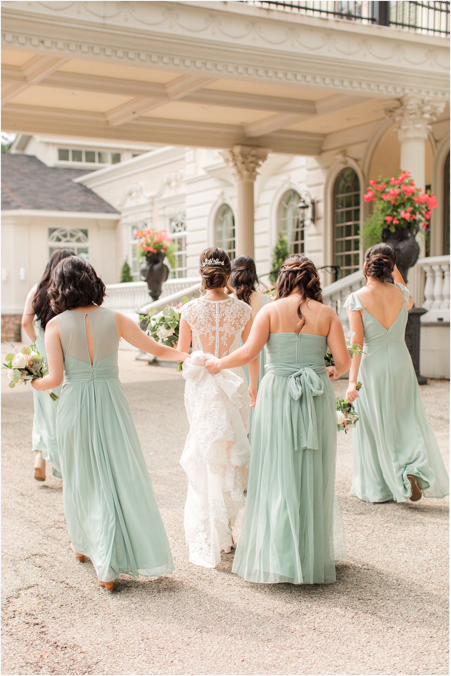 bridesmaids in mint dresses hold up bride's skirt walking outside Ashford Estate