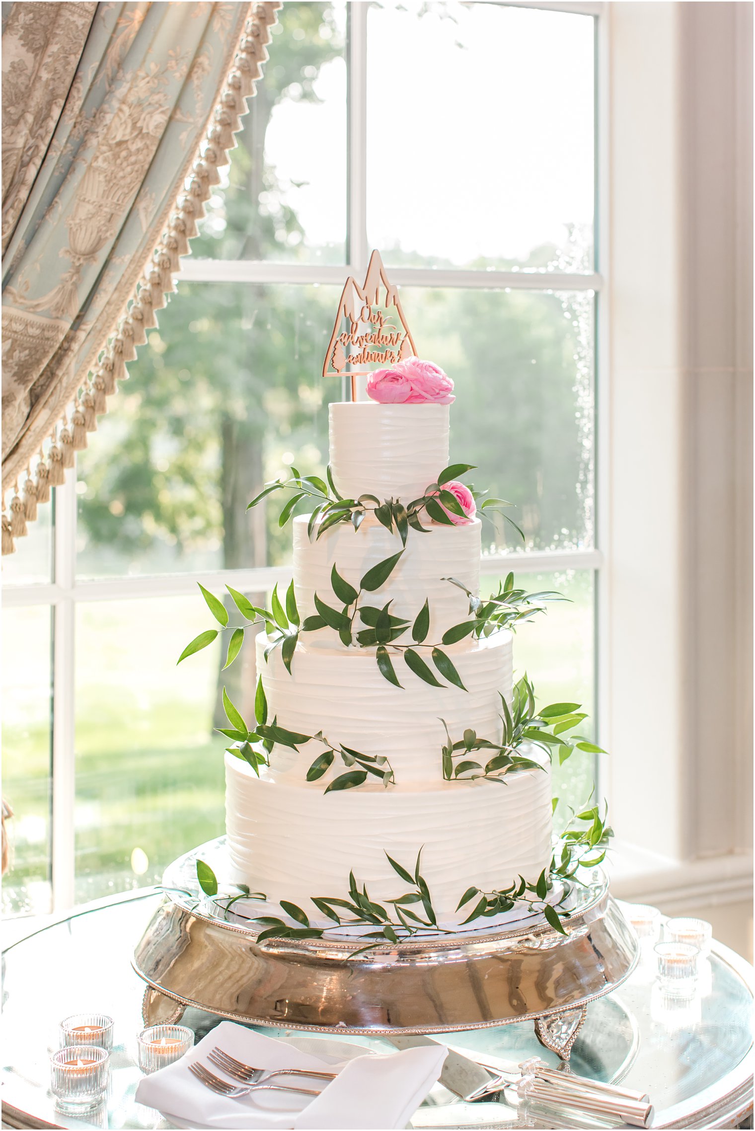 tiered wedding cake with wooden cake topper and pink flowers 