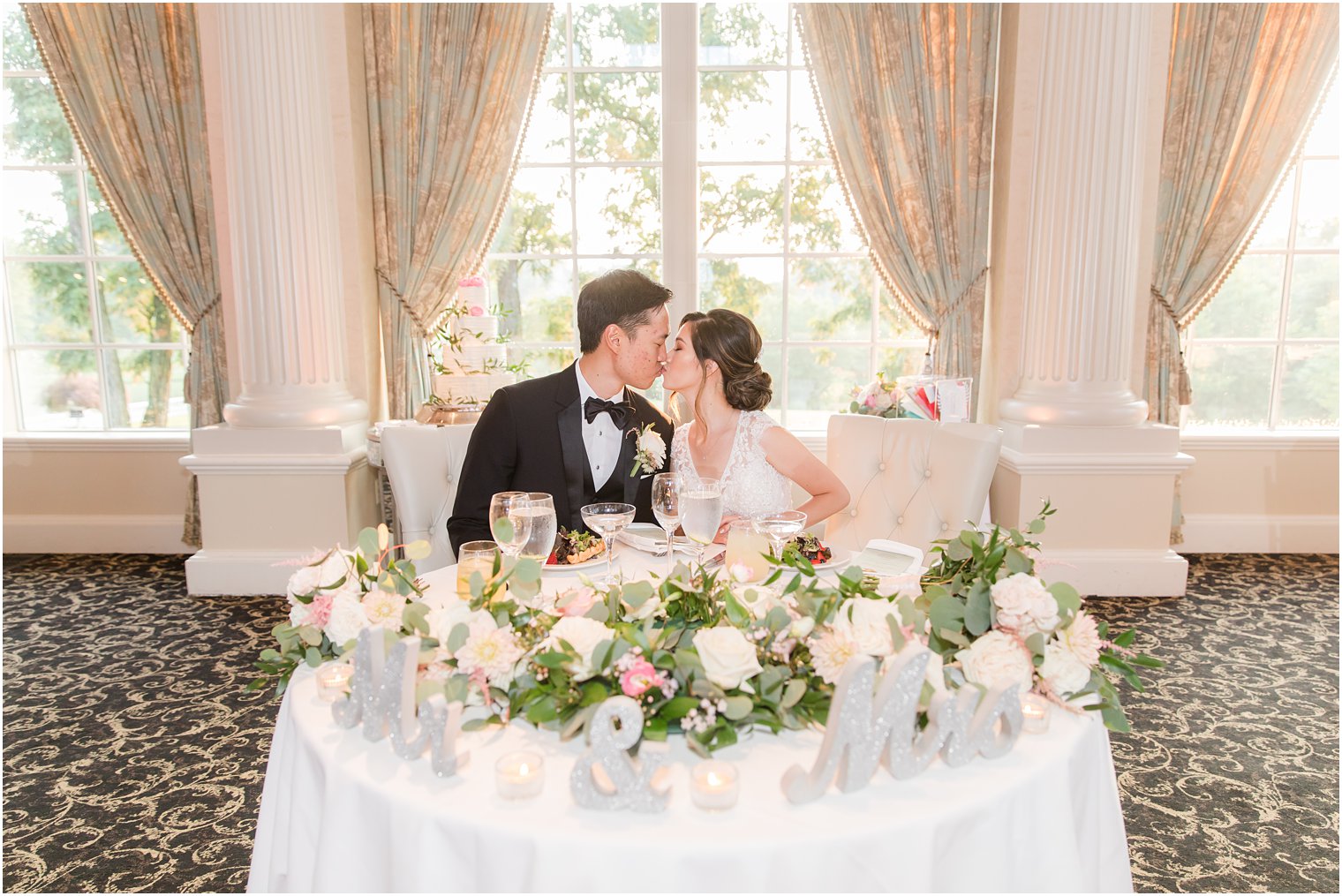 bride and groom kiss at sweetheart table during Ashford Estate wedding reception