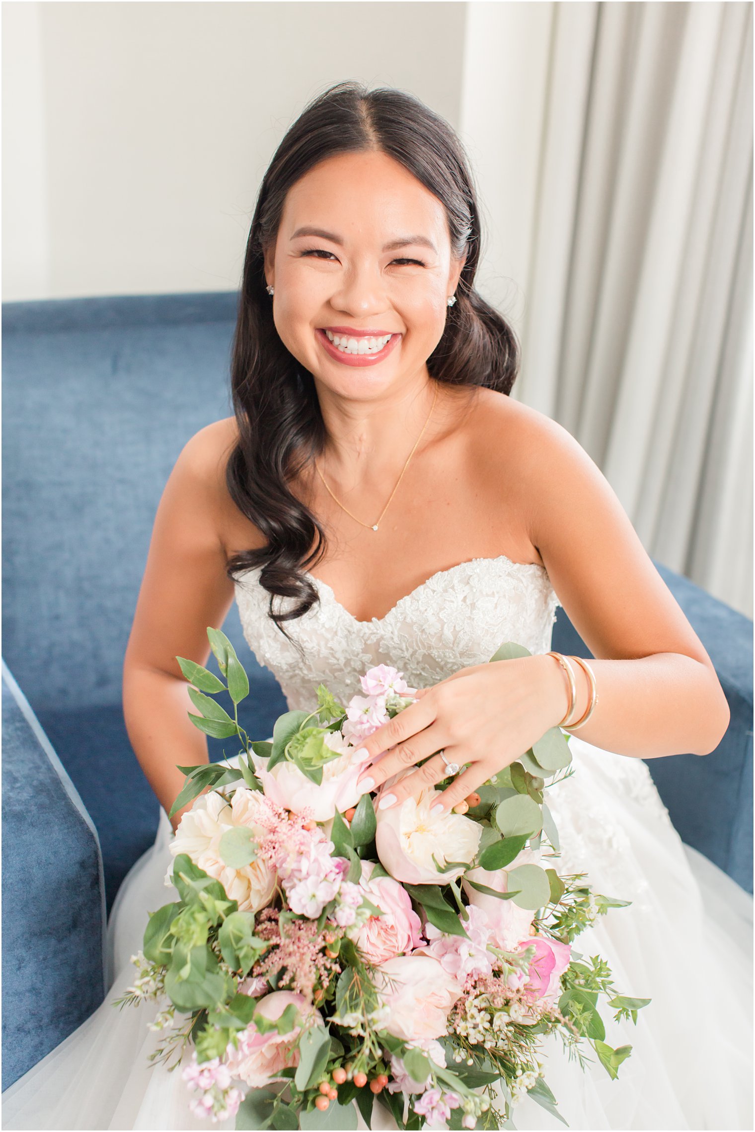 bride sits in blue chair holding bouquet before PA wedding