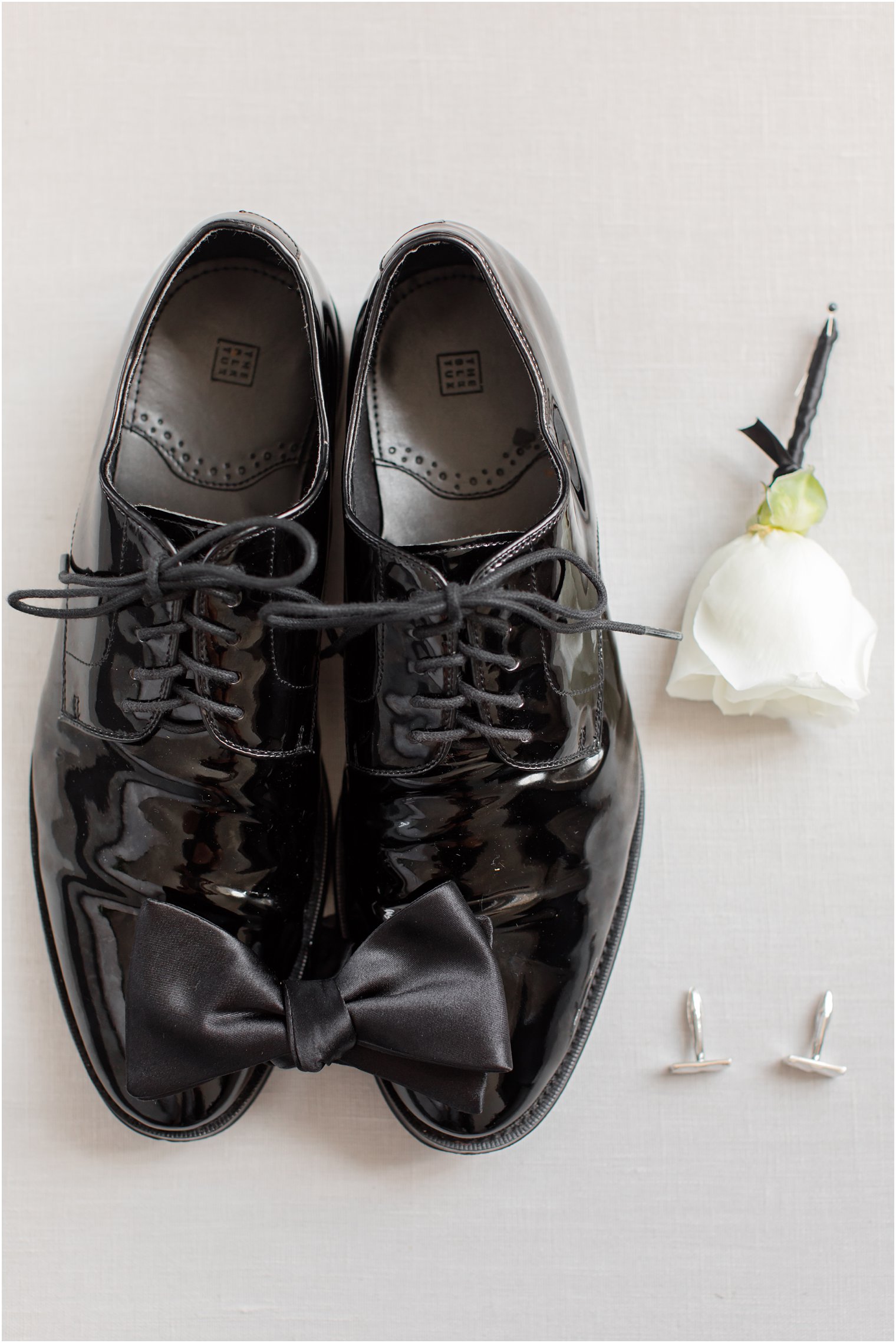 groom's classic black shoes and ivory boutonnière 