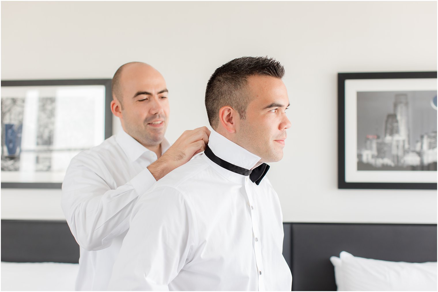 groomsmen helps groom with black bowtie