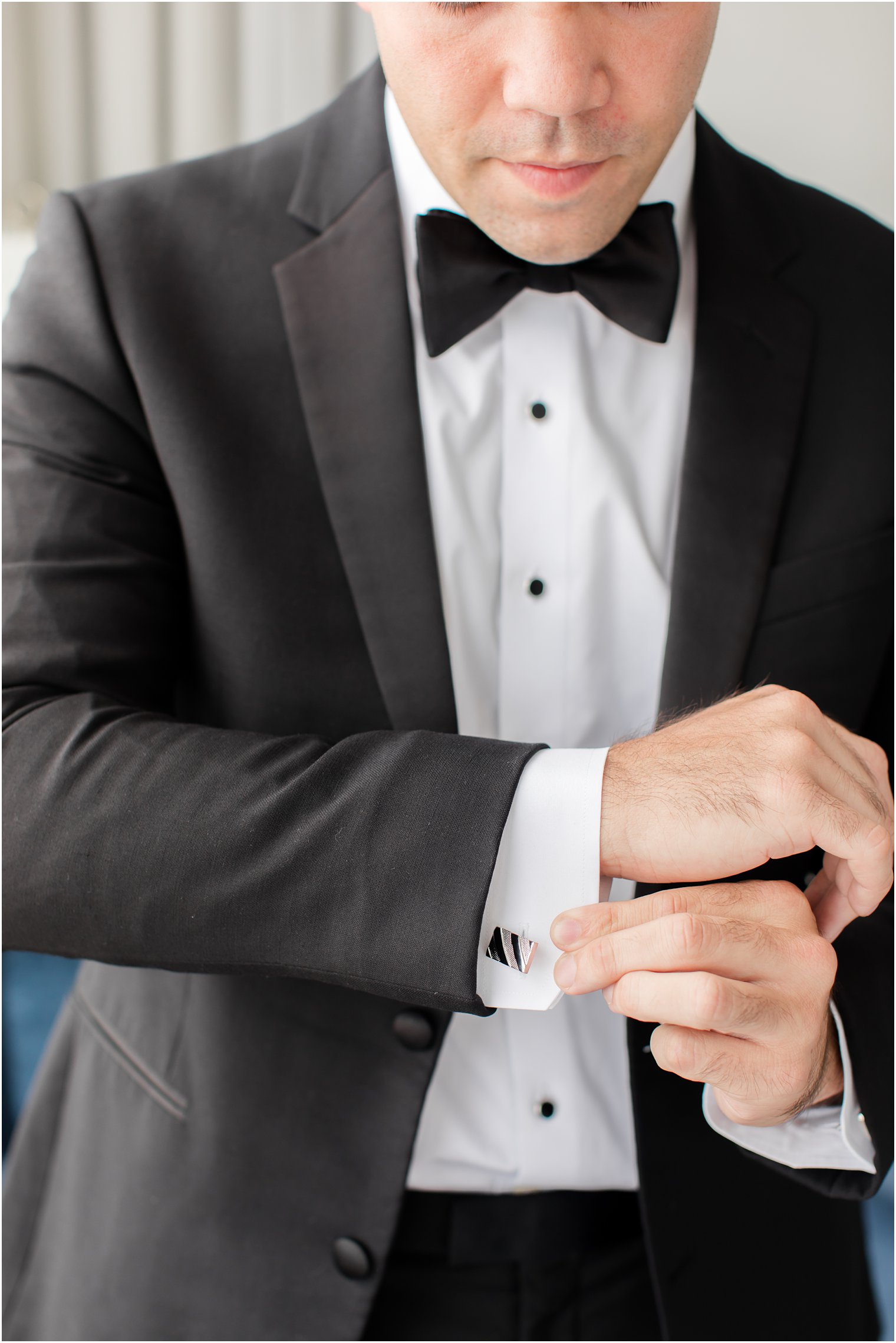 groom in classic tux adjusts custom cufflinks