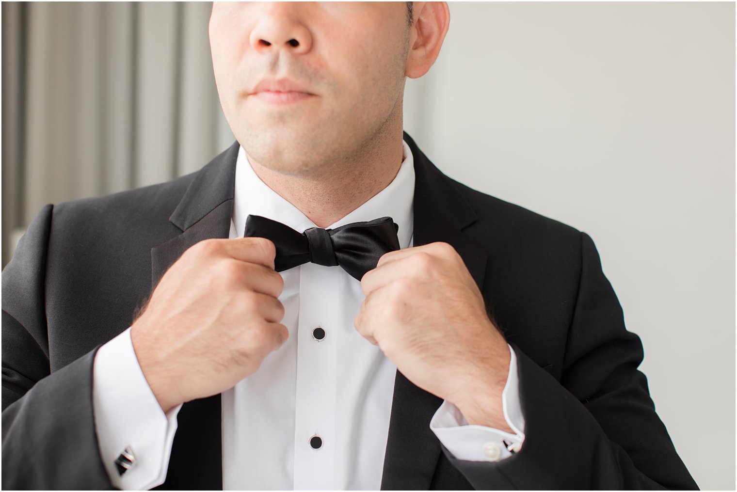 groom adjusts bowtie on classic tux for PA wedding