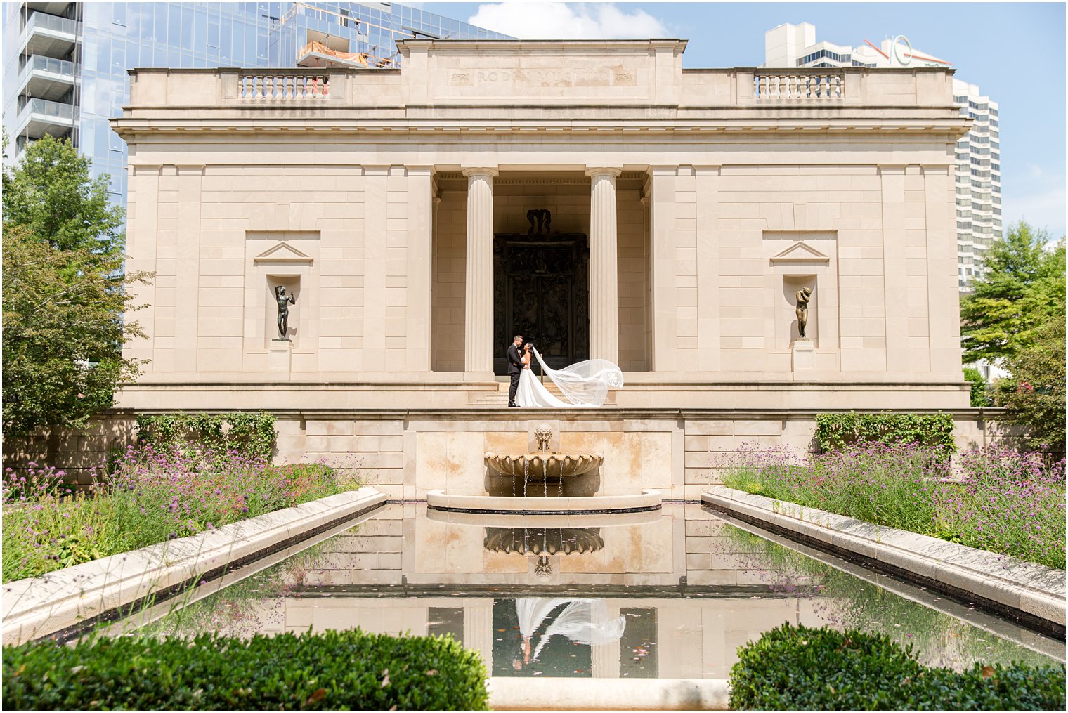 bride and groom pose on steps of Rodin Museum in front of pond