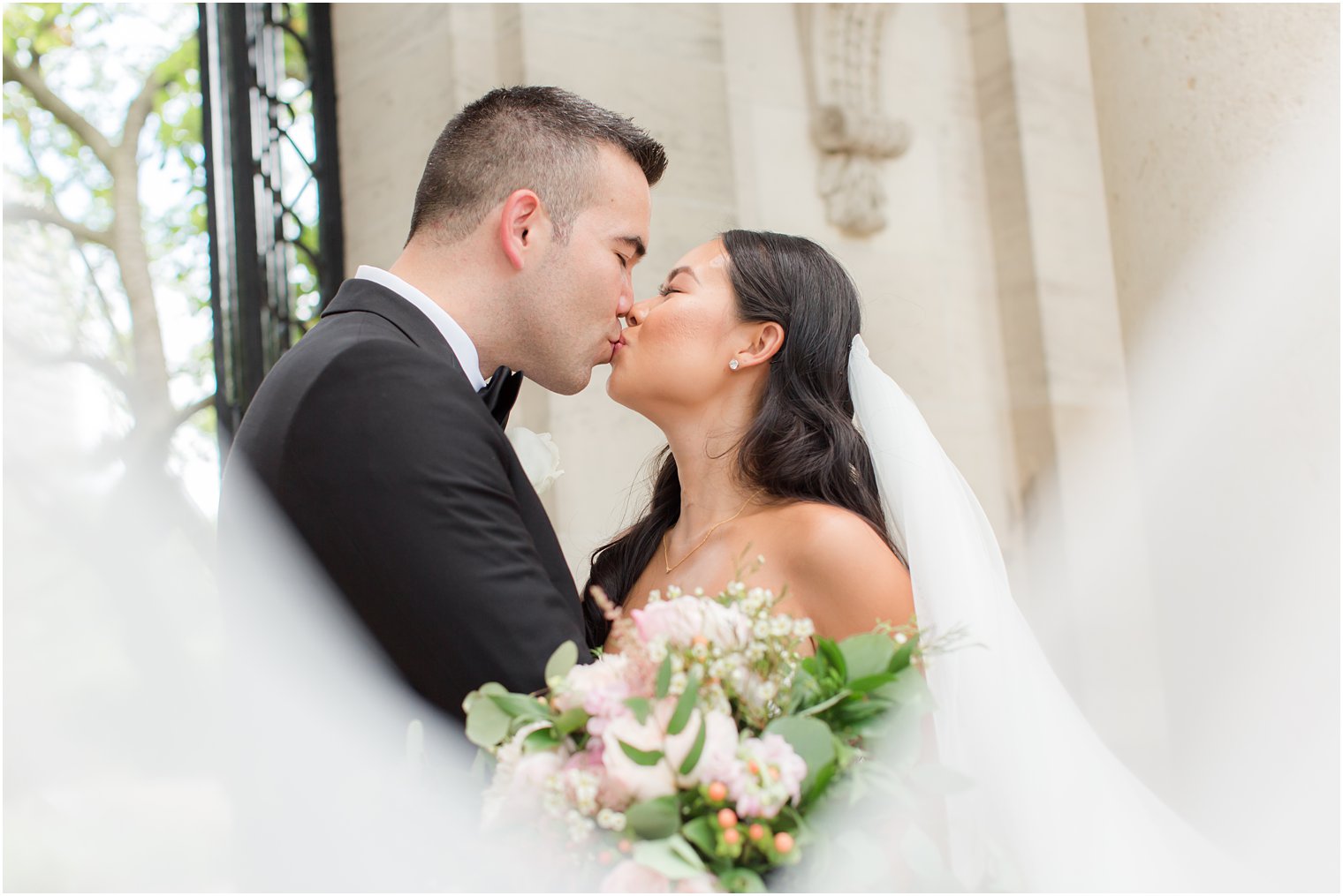 bride and groom kiss with veil in front of them at Rodin Museum