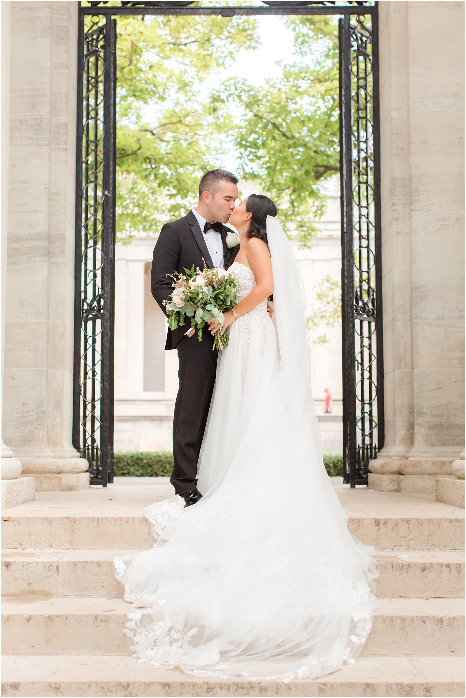 newlyweds kiss between wrought iron gates at Rodin Museum