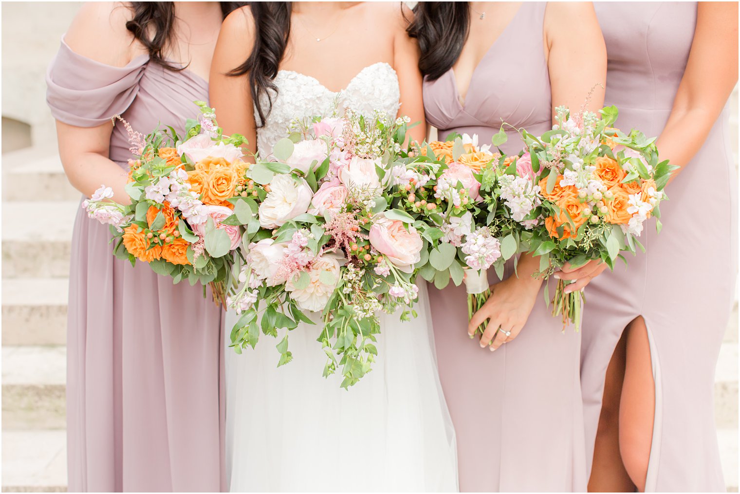 bride and bridesmaids pose on steps of Rodin Museum with pastel bouquets 
