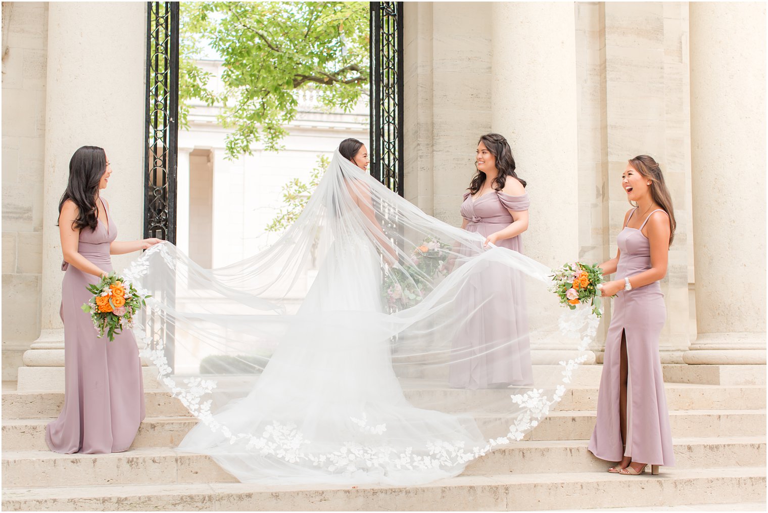bridesmaids in mauve gowns hold bride's veil out in Philly PA