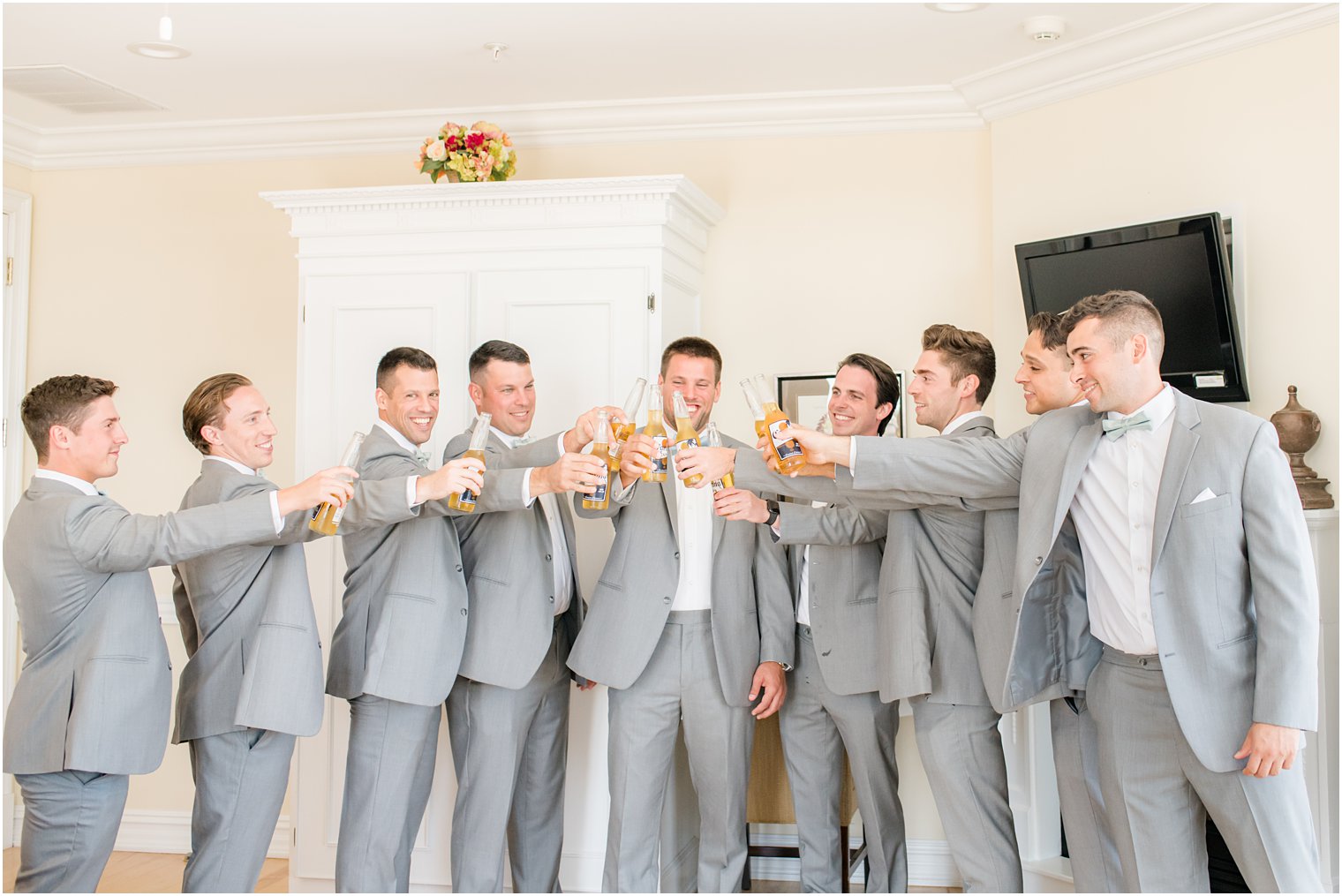 groom and groomsmen in grey suits toast champagne